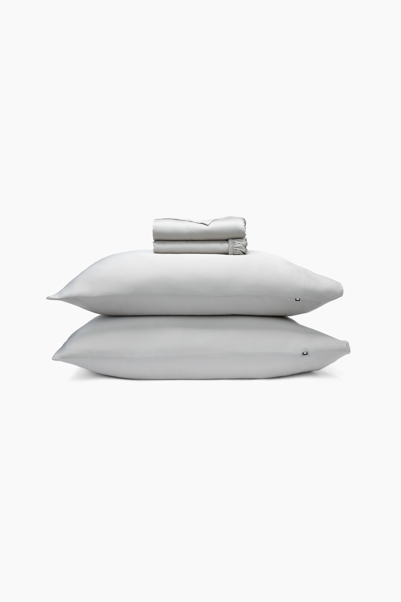Gray pillows and folded sheets on a white background