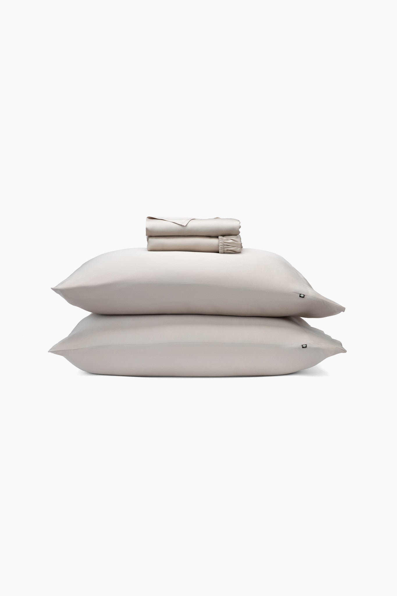 Beige pillows and folded sheets on a white background