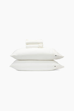 Stack of white pillows and folded sheets on a white background