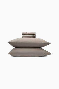 Set of medium brown pillows and a folded sheets on a white background