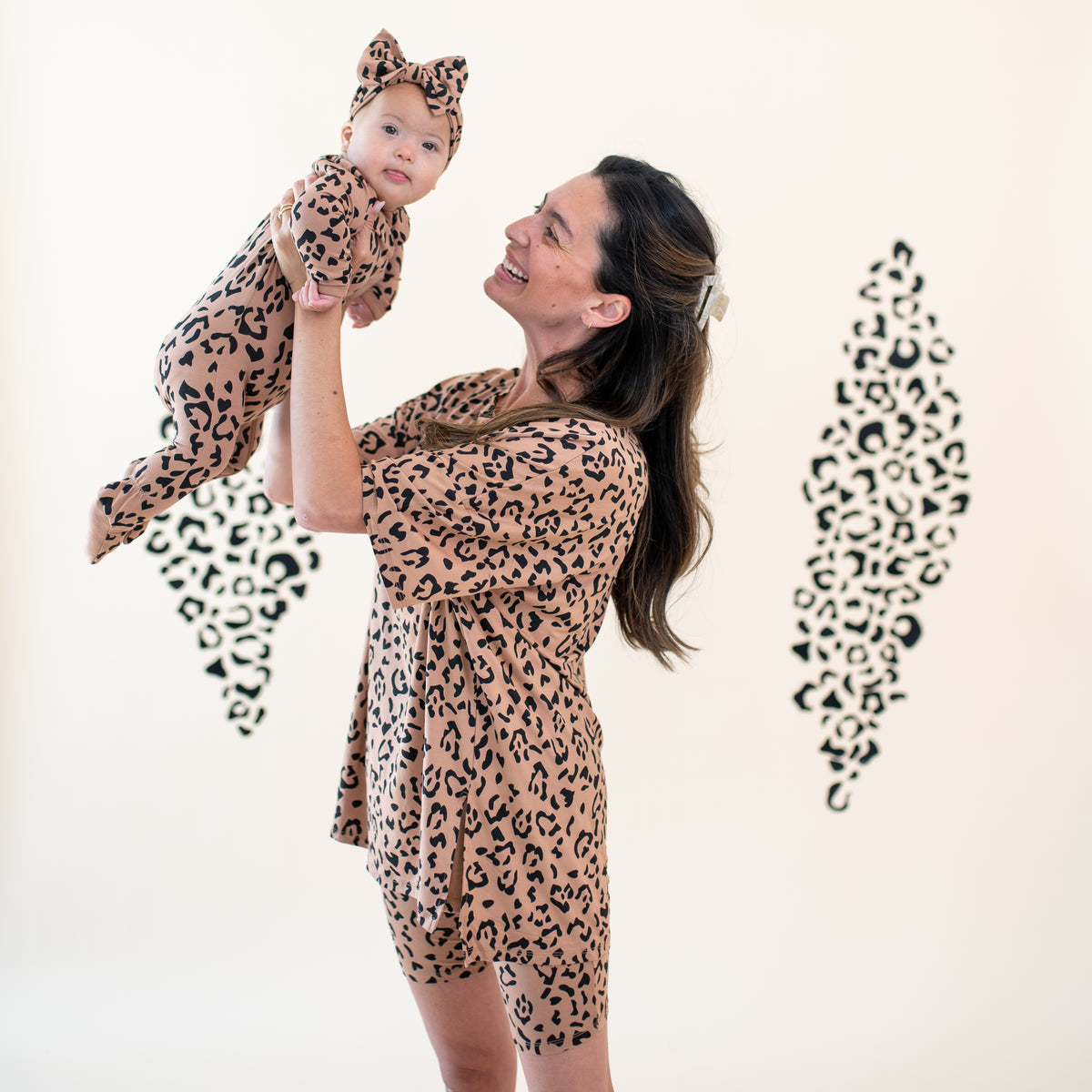 Mother wearing Women’s Biker Short Set in Latte Leopard holding baby in matching Mommy and Me pajamas and bow headband