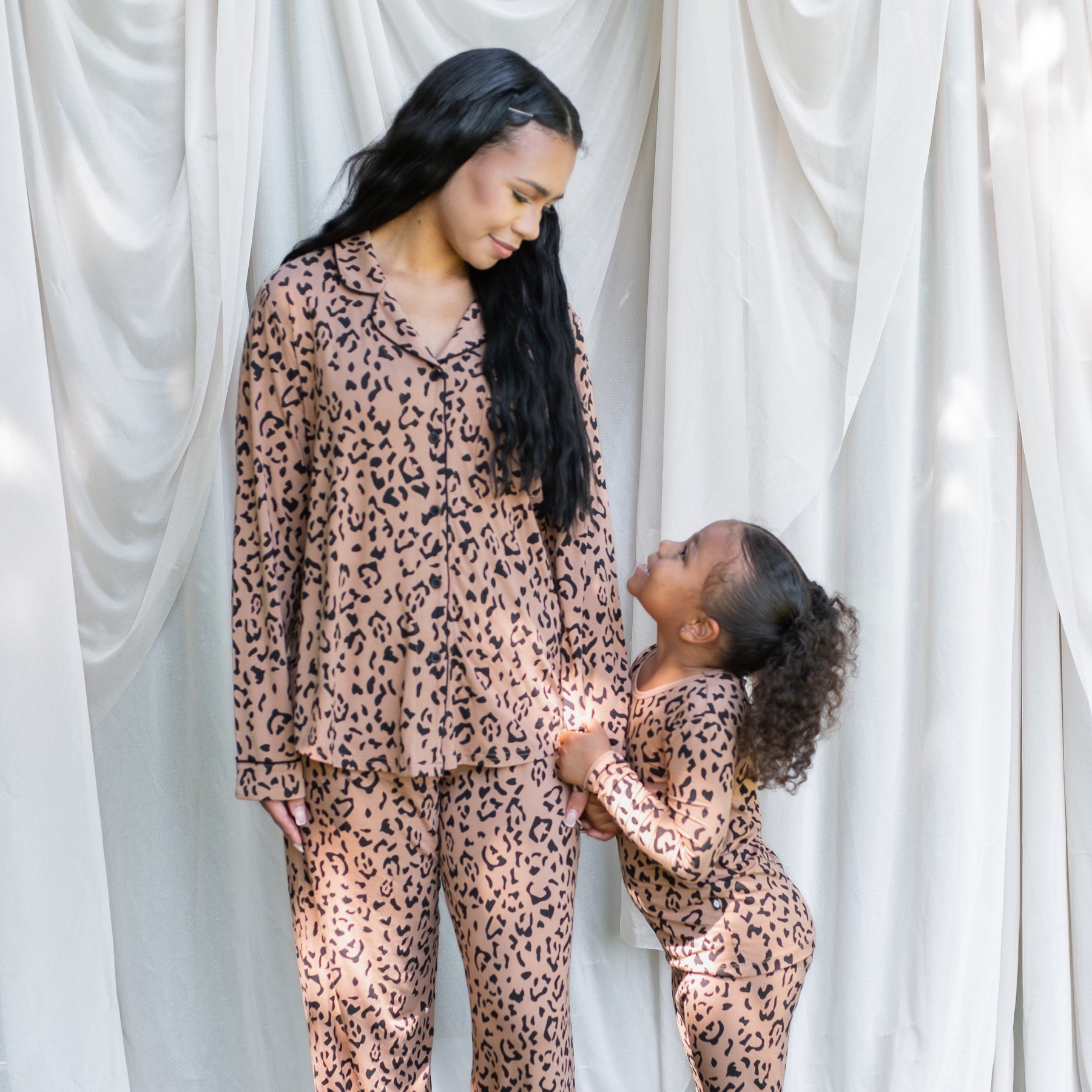 Mother and daughter looking at one another matching in Latte Leopard pajamas