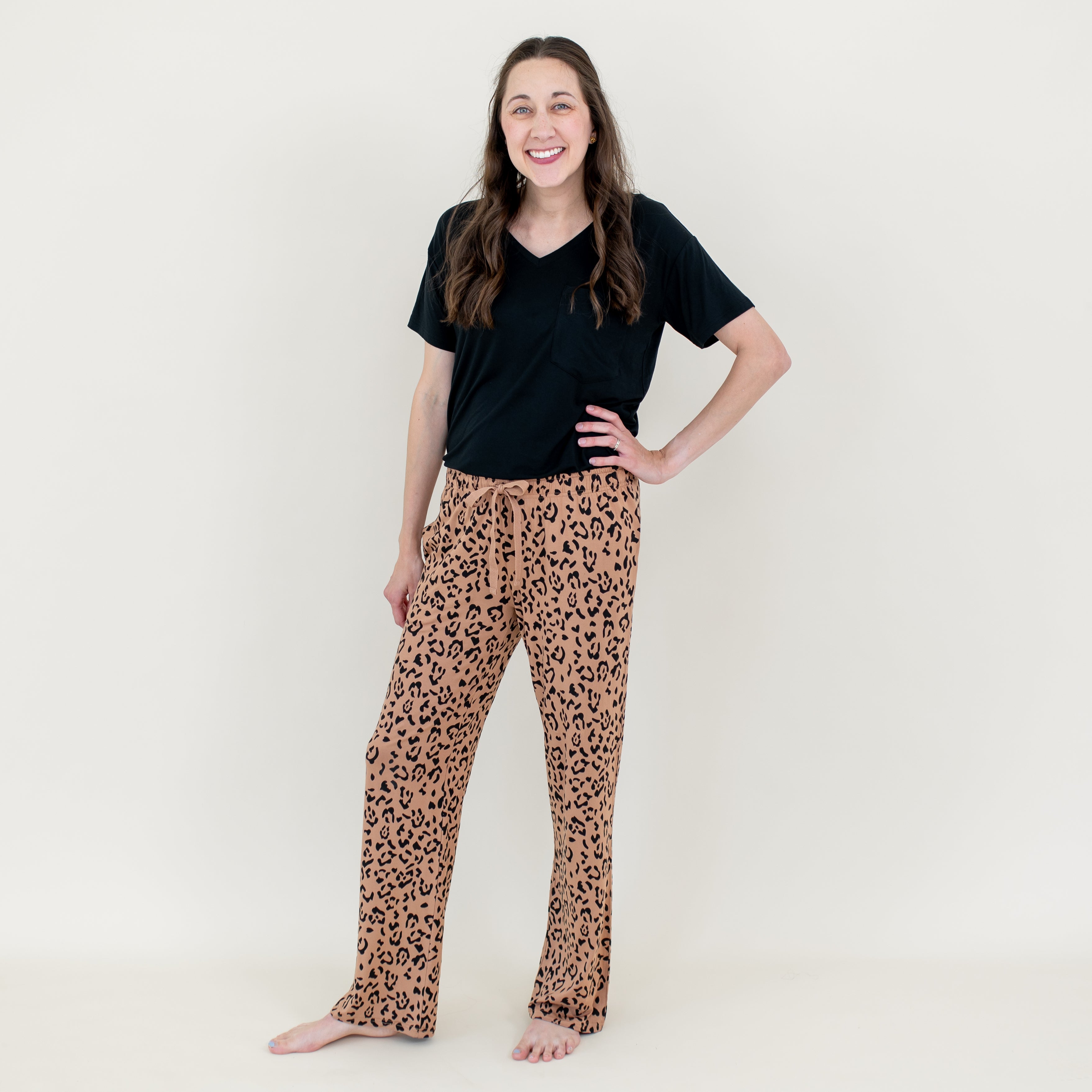 Smiling female model standing with her hand on her hip wearing the Women's Lounge Pants in Latte Leopard with a Women's V-neck in Midnight