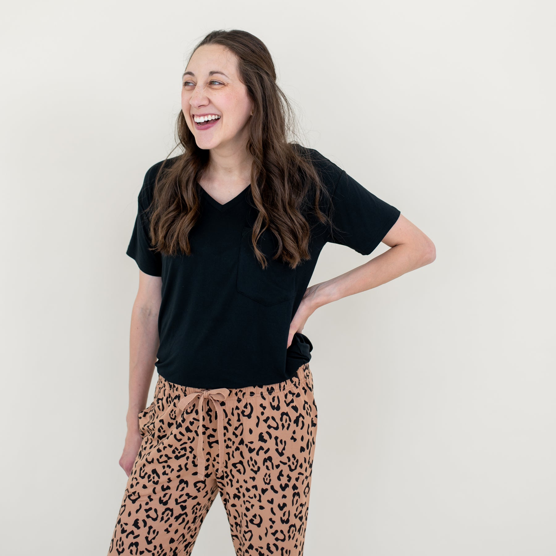 Close up of the Women's Lounge Pants in Latte Leopard on a smiling model paired with a women's midnight v-neck