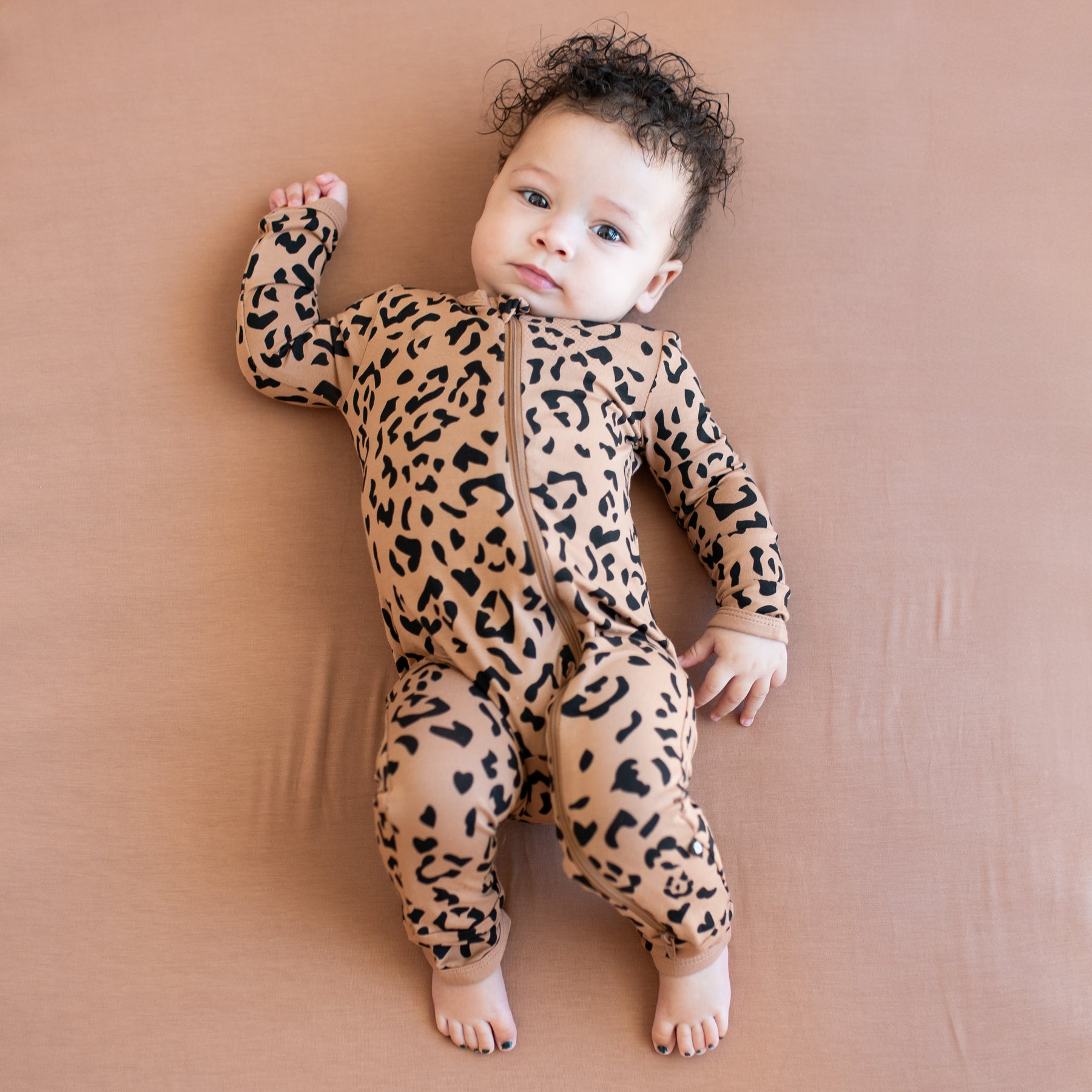 Infant laying on a latte blanket wearing the Zippered Romper in Latte Leopard
