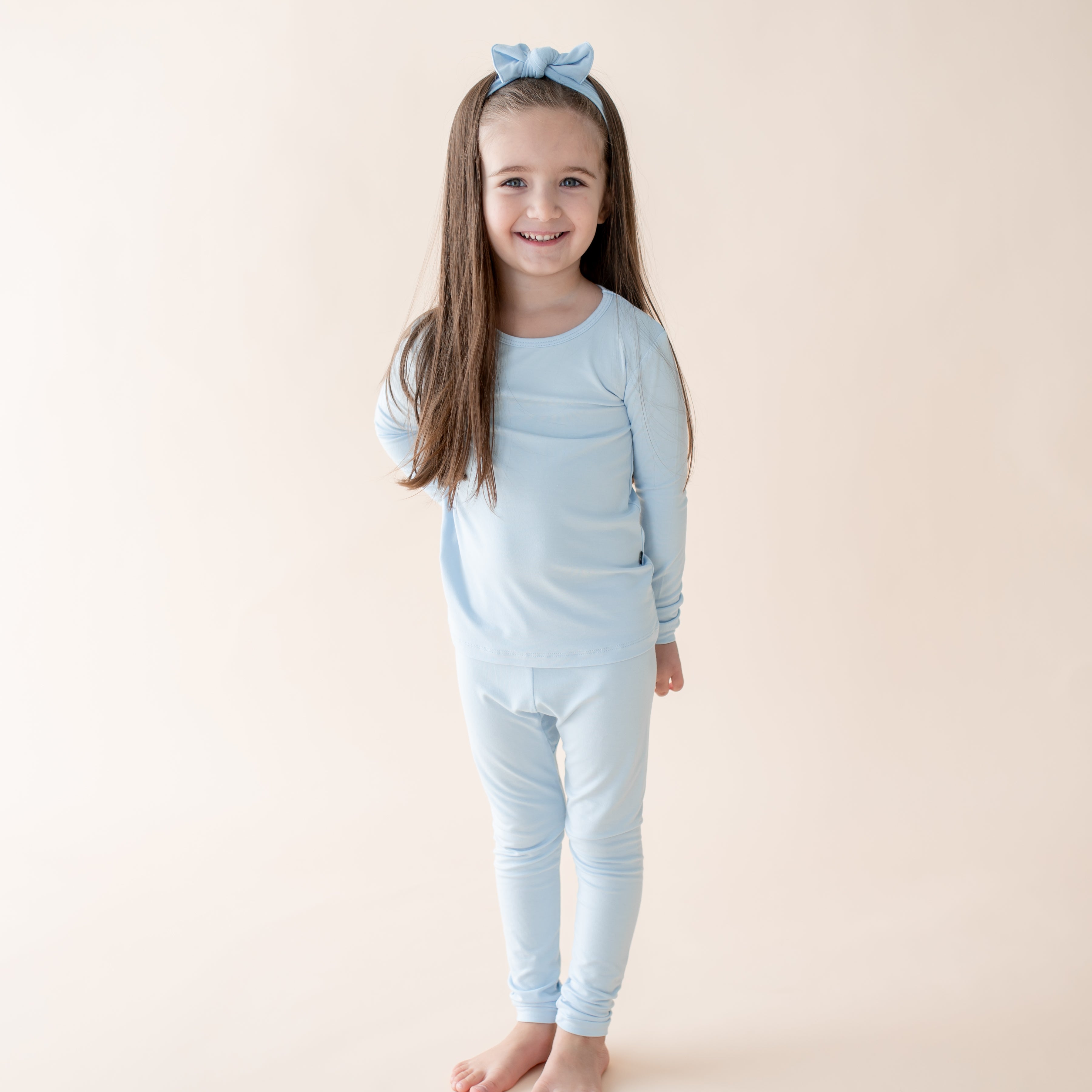 Young girl wearing light blue long sleeve pajama set with bow