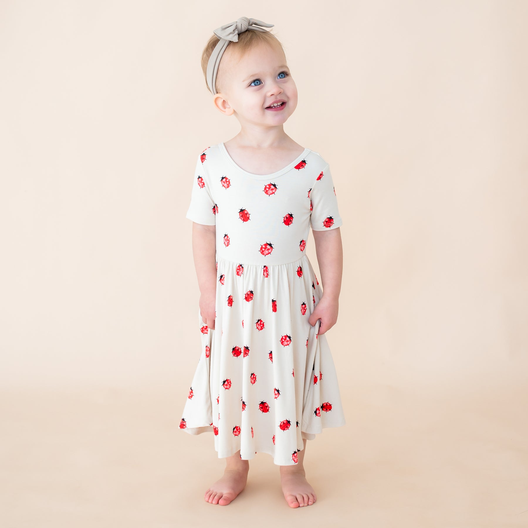 Toddler smiling wearing twirl dress in Love Bug