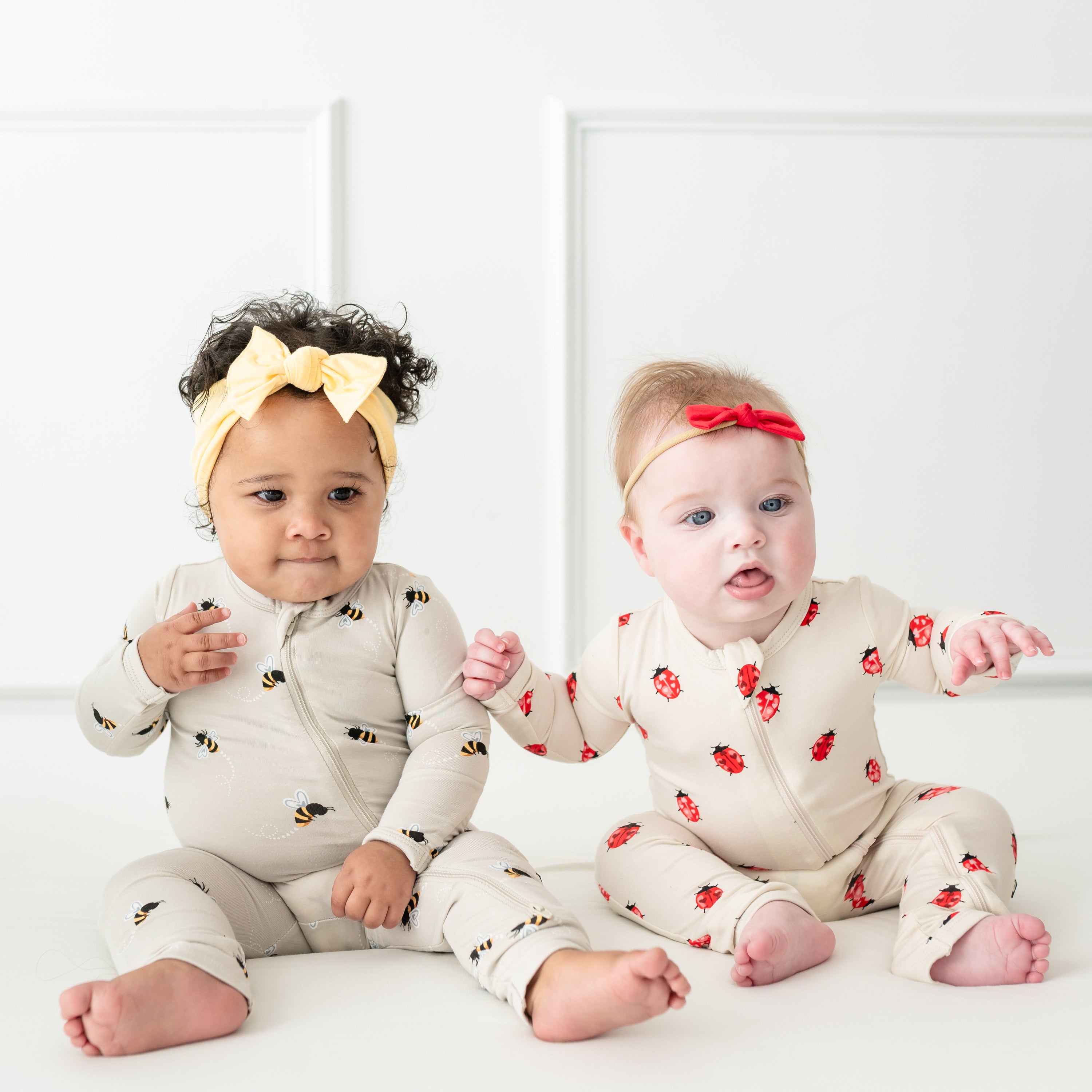 Babies sitting wearing Bee Mine and Love Bug zippered rompers