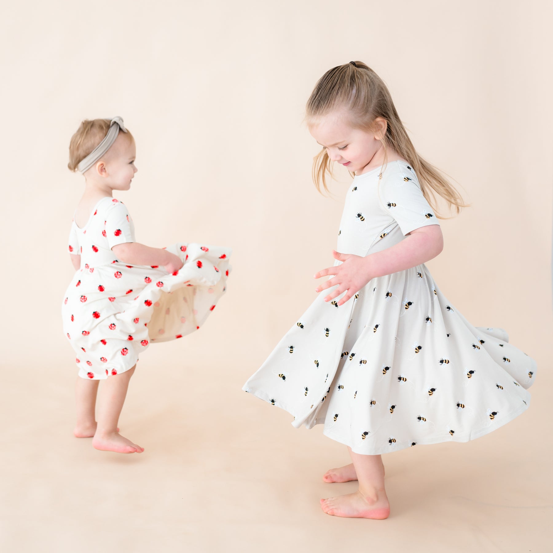 Two toddlers twirling in twirl dresses in the prints Love Bug and Bee Mine