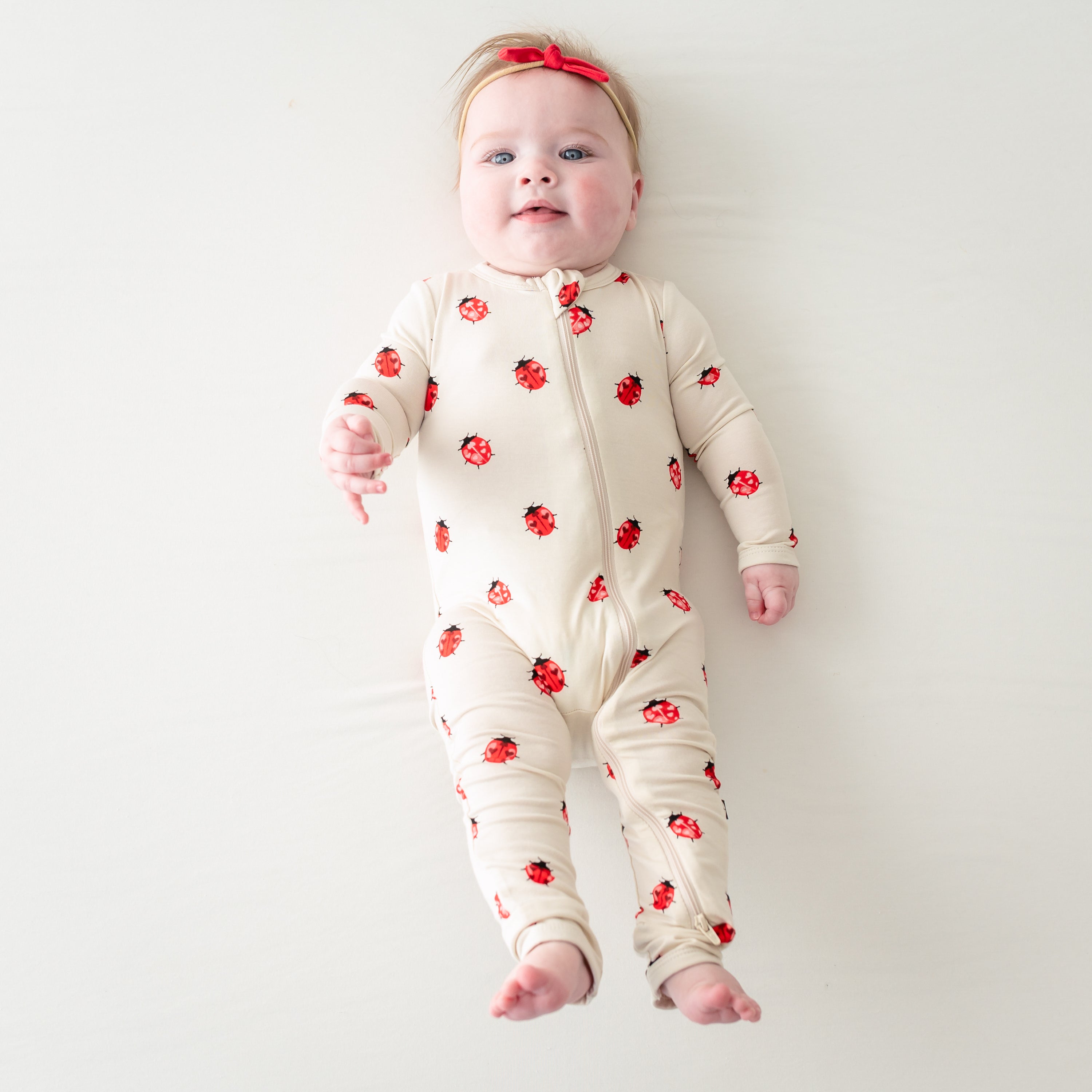 Baby laying down wearing Love Bug zippered romper