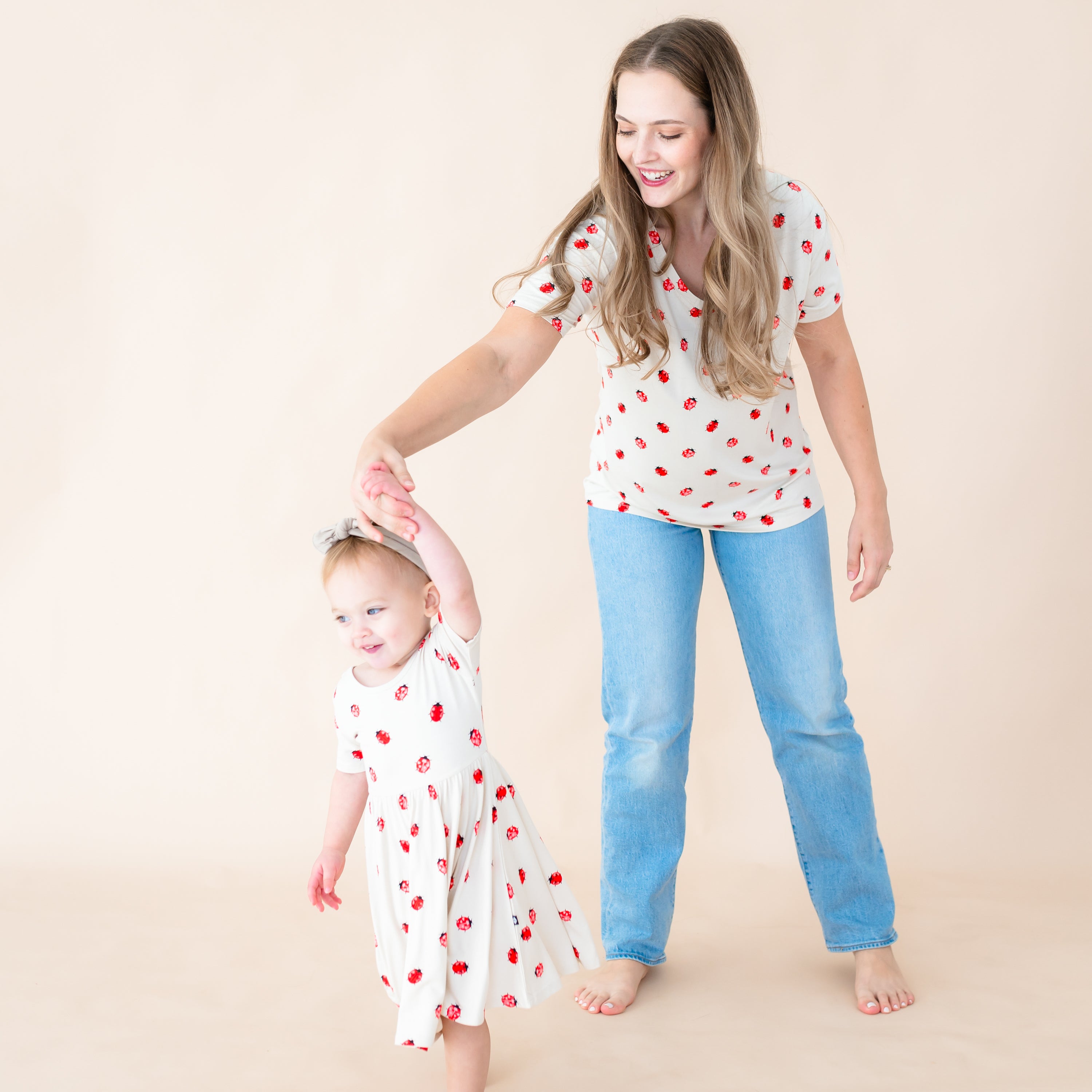 Toddler wearing twirl dress in Love Bug  being twirled by mom in a matching Love Bug v-neck tee