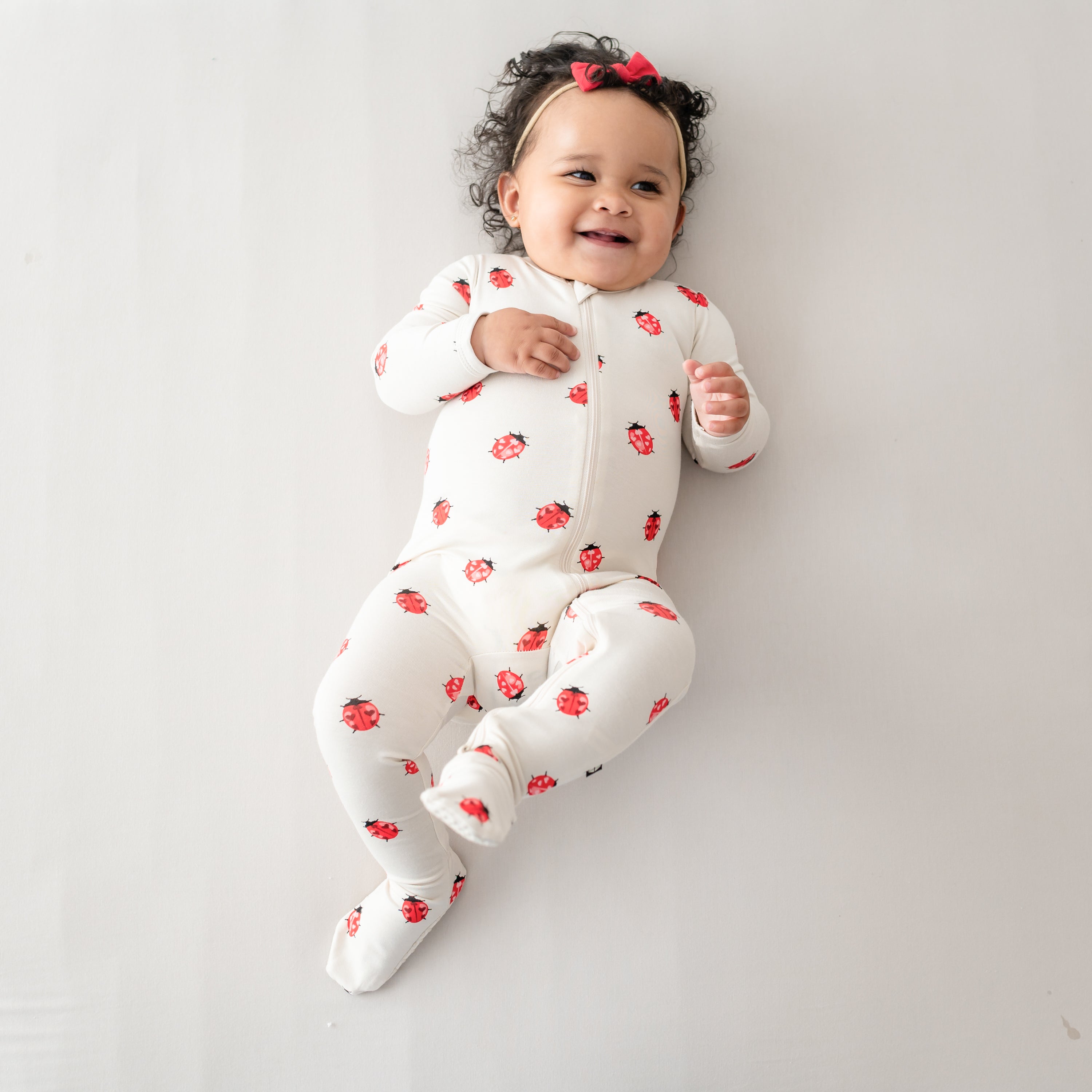 Baby smiling and laying down wearing Love Bug Zippered Footie