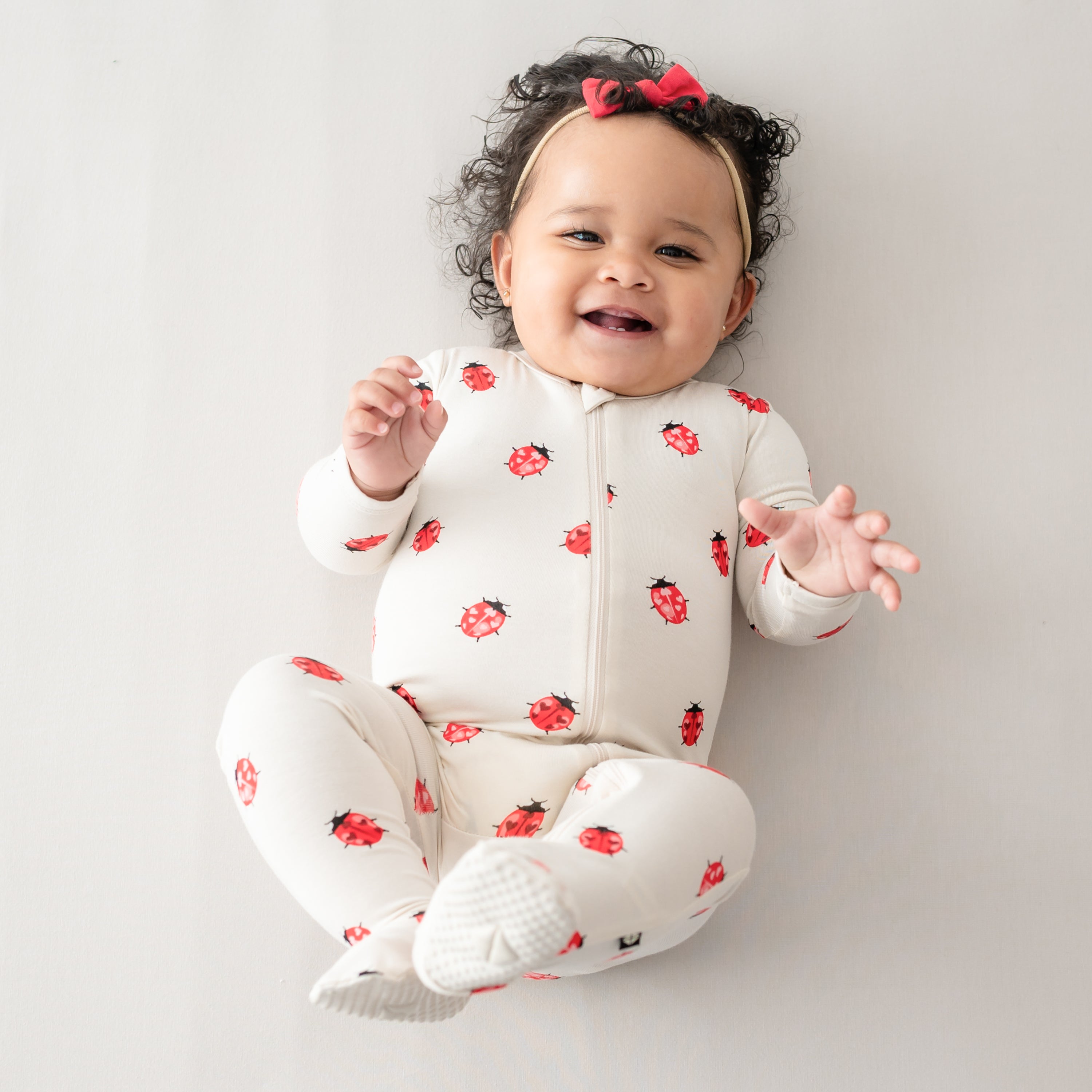 Baby smiling and laying down wearing Love Bug Zippered Footie