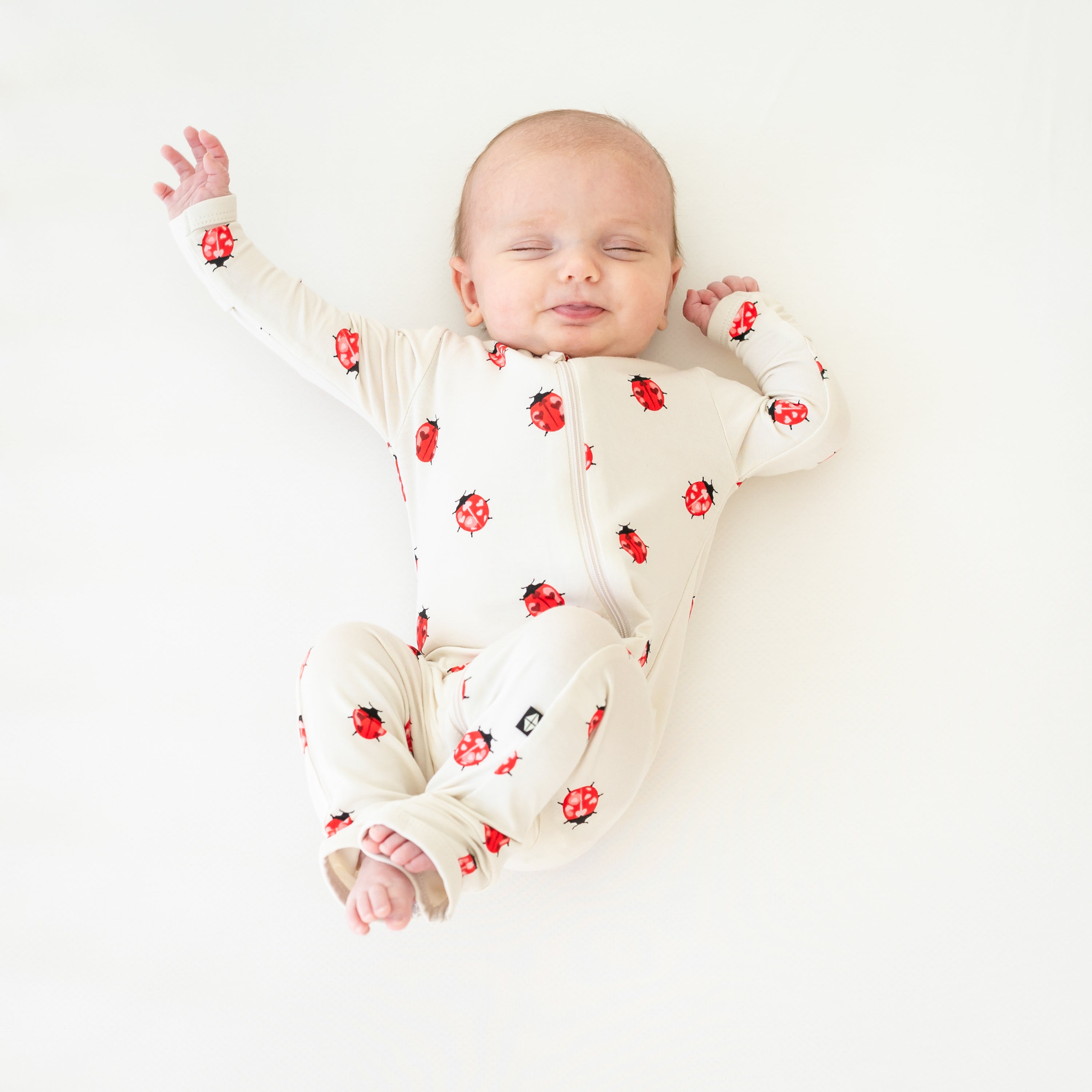 Sleeping baby stretching wearing Love Bug zippered romper