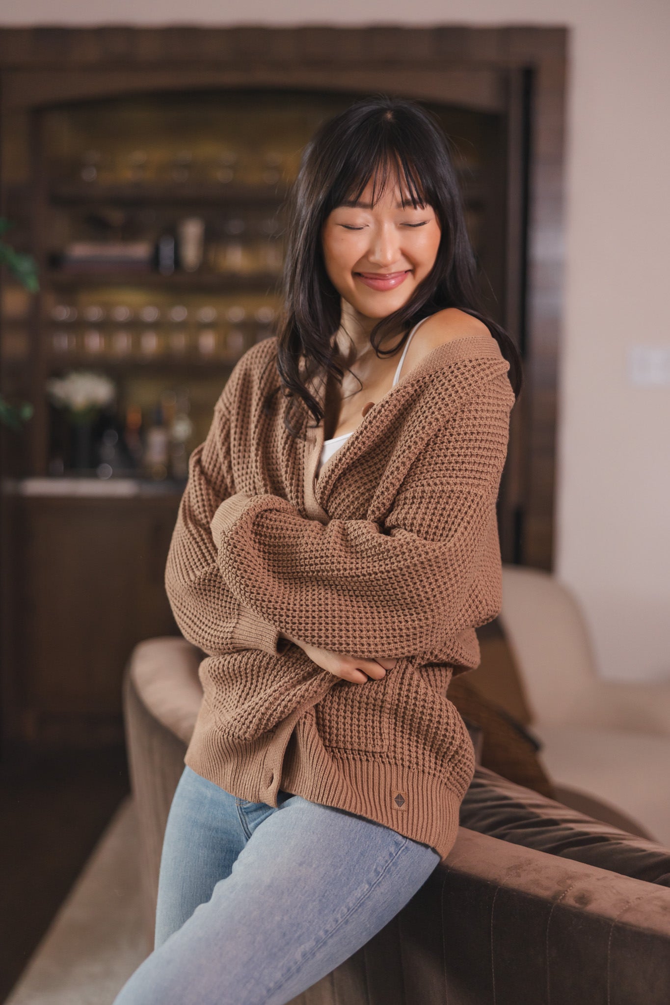 Modal posing in Chunky Knit Women's Waffle Cardigan in Latte over white camisole and blue jeans
