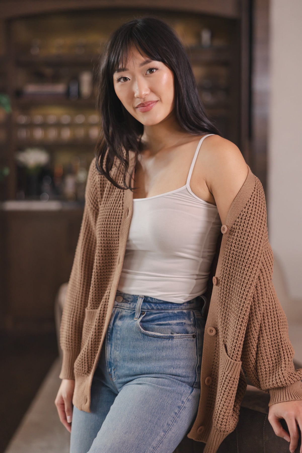 Modal wearing Chunky Knit Women's Waffle Cardigan in Latte over white camisole and blue jeans
