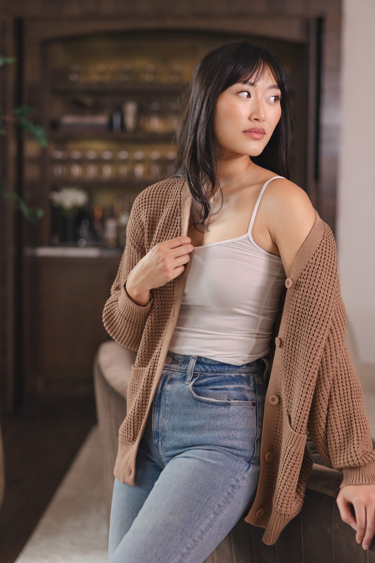 Modal posing in Chunky Knit Women's Waffle Cardigan in Latte over white camisole and blue jeans