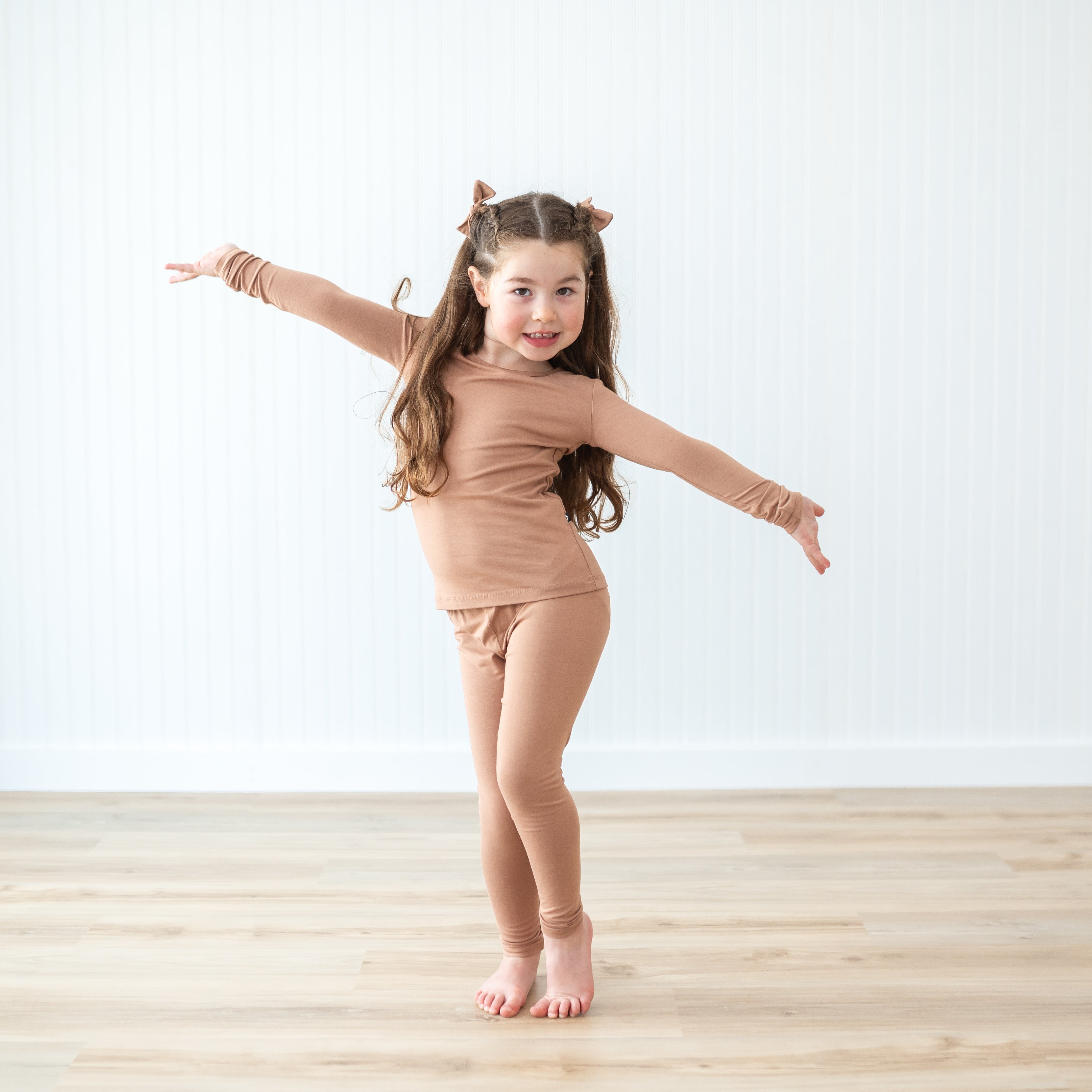 Girl model posing with her both arms outstretched wearing the Long Sleeve Pajamas in Latte