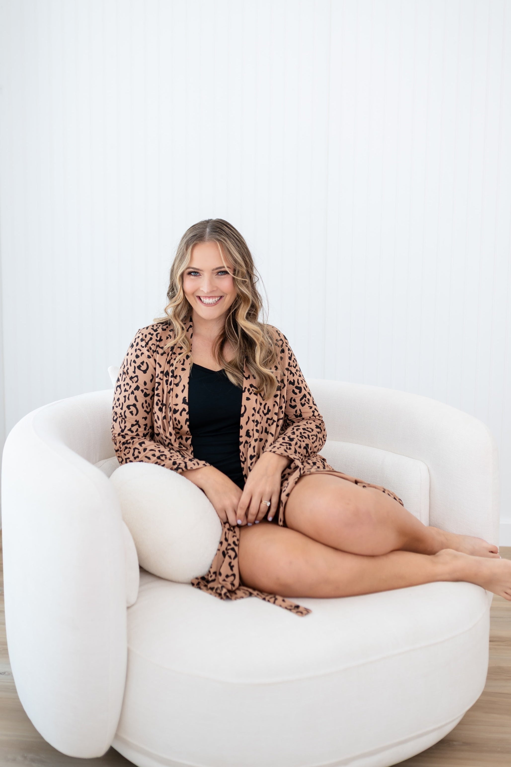 woman wearing leopard print robe and black tank set sitting on white chair