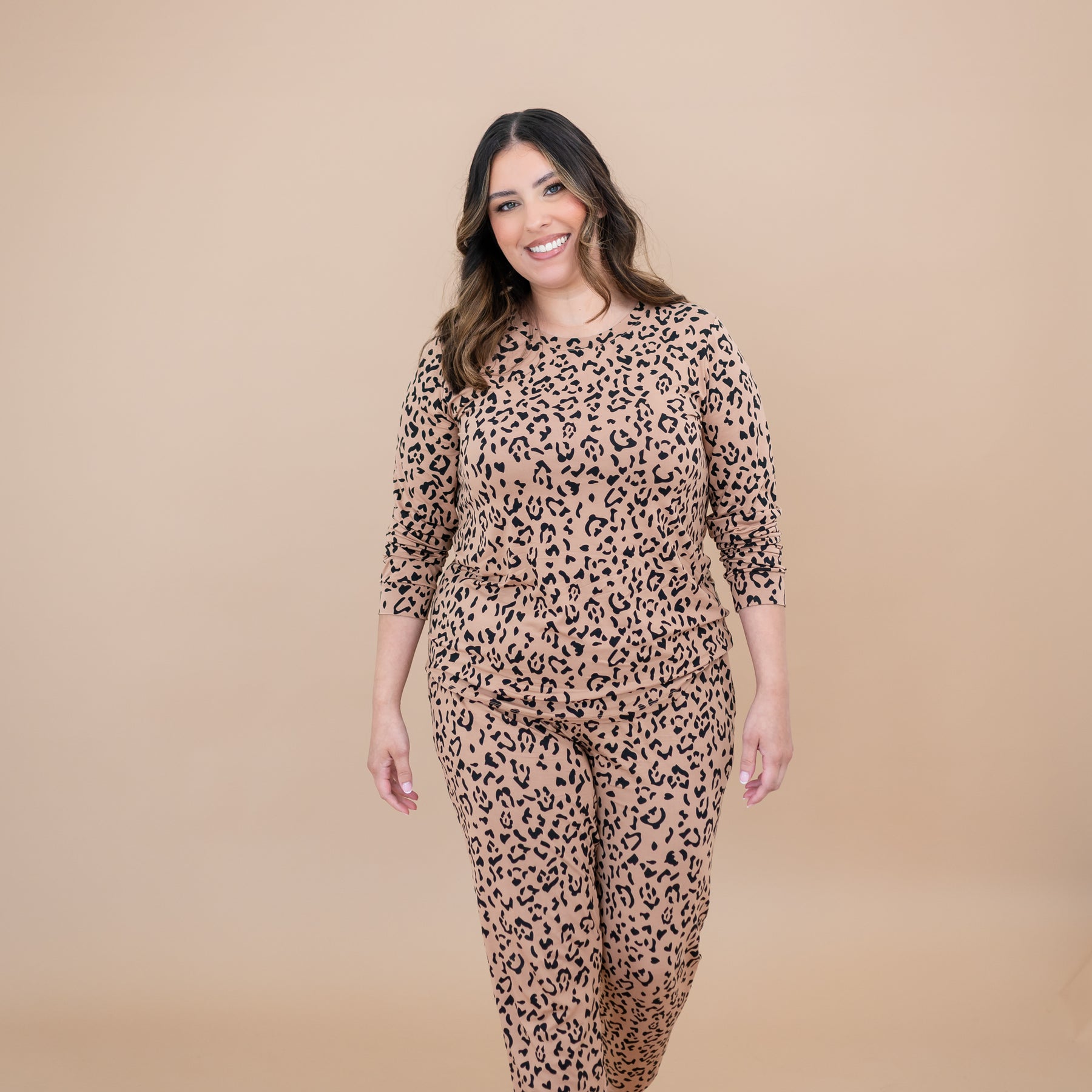 Smiling female model walking wearing the Women's Jogger Pajama Set in Latte Leopard in front of a taupe background