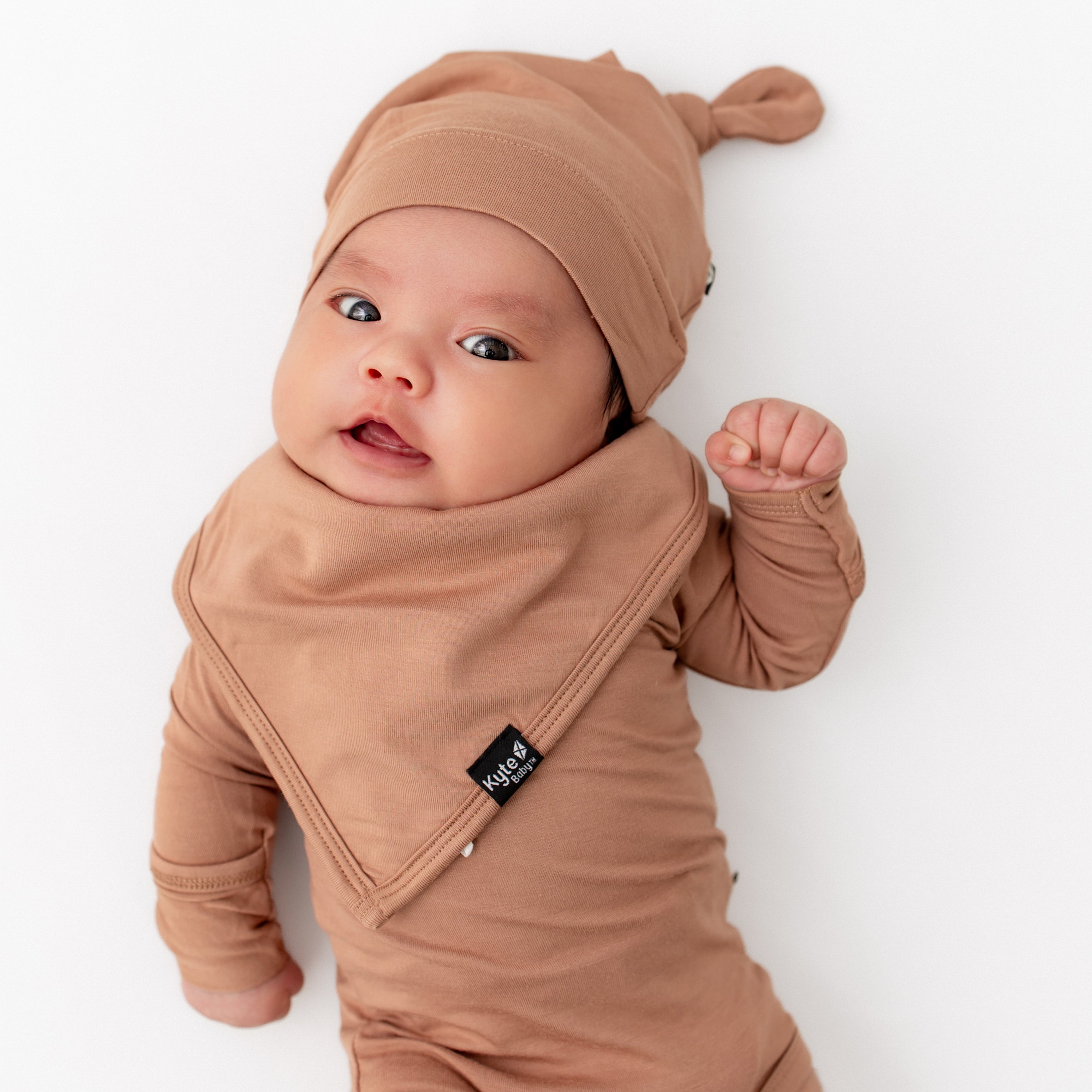 Newborn wearing the Knotted Cap in Latte with matching bib and long sleeve bodysuit