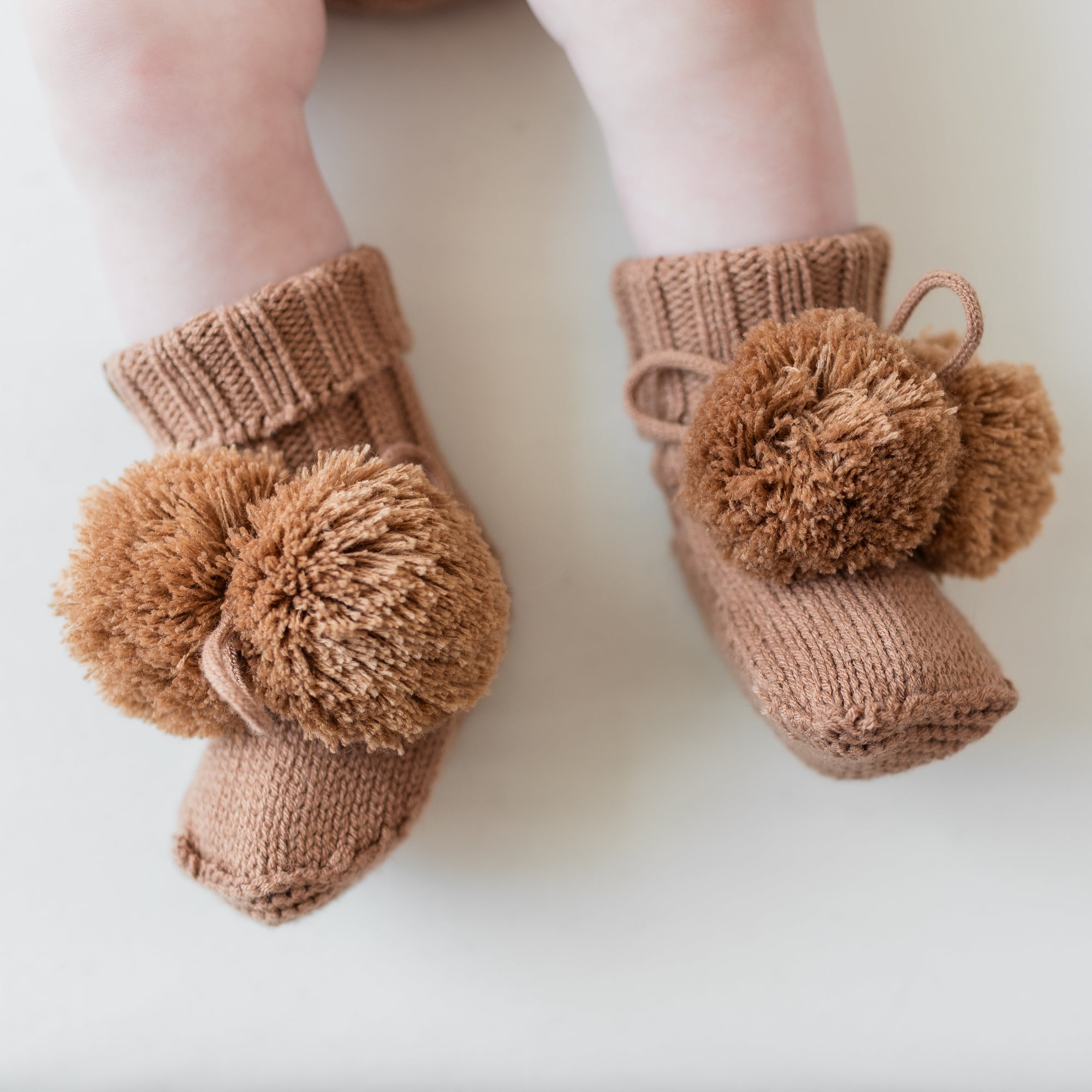 Close up of the Knit Booties in Latte shown on an infant