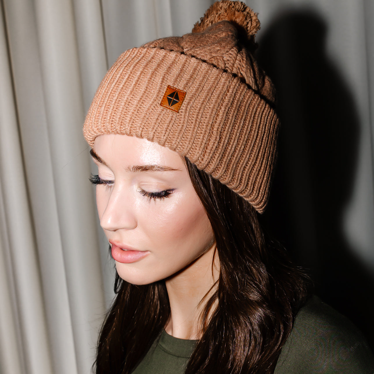 Close up of the Cable Knit Adult Pom Beanie in Latte shown on a female model