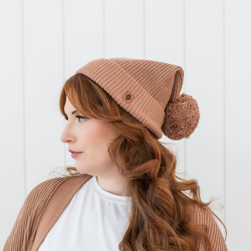 Close up of the Chunky Knit Adult Pom Beanie in Latte shown on a female model