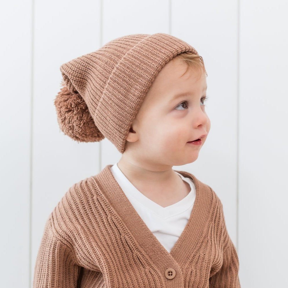 Close up of the Chunky Knit Pom Beanie in Latte shown on a toddler