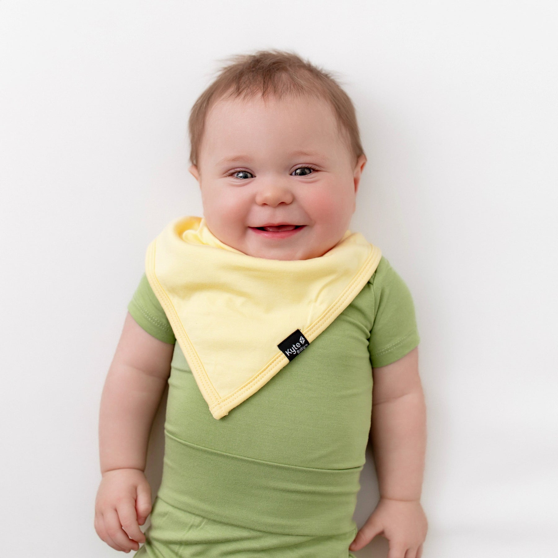 baby wearing kyte baby bodysuit in honu and lilikoi bib