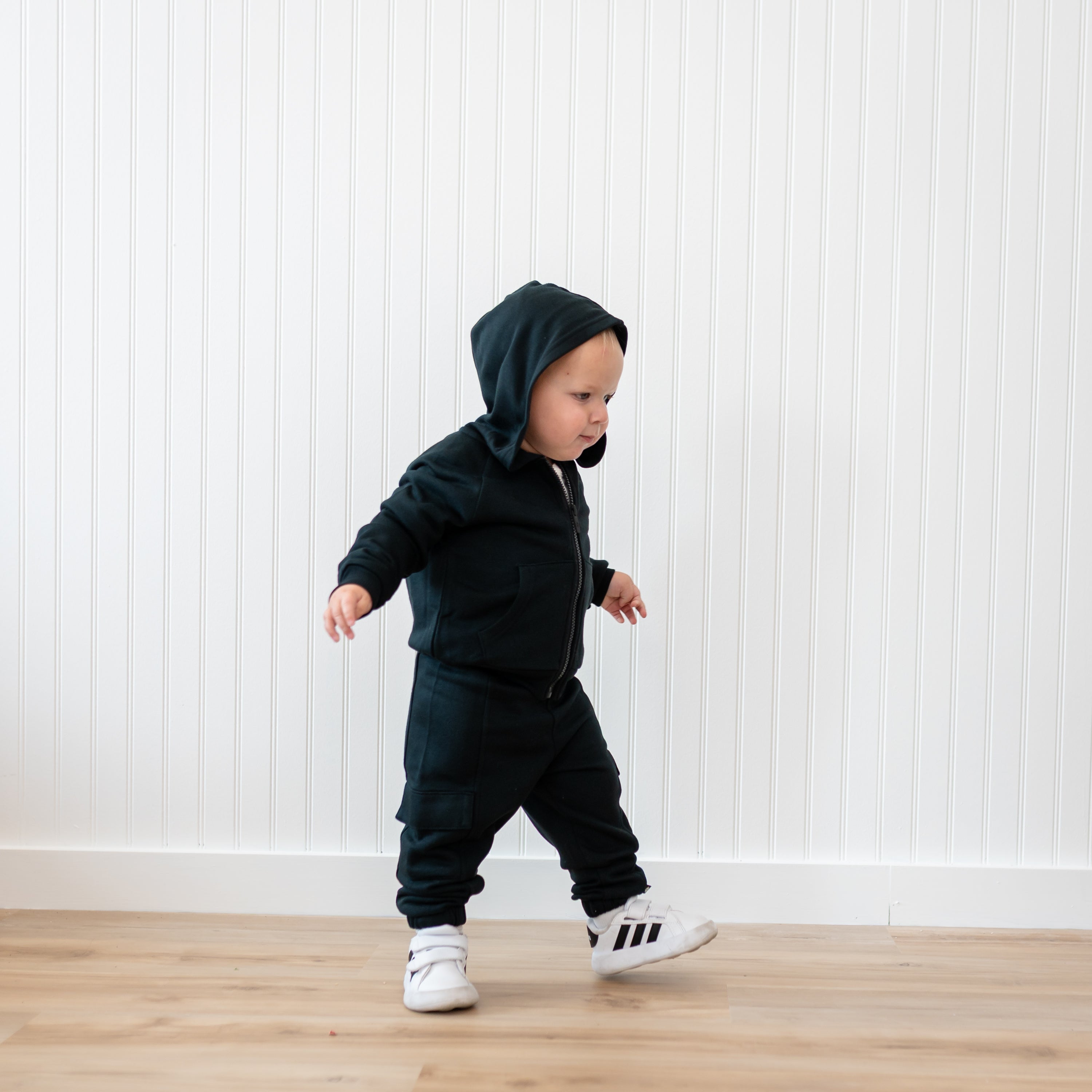 Young toddler walking wearing the Fleece Zip Up Hoodie in Midnight and matching fleece cargo pant