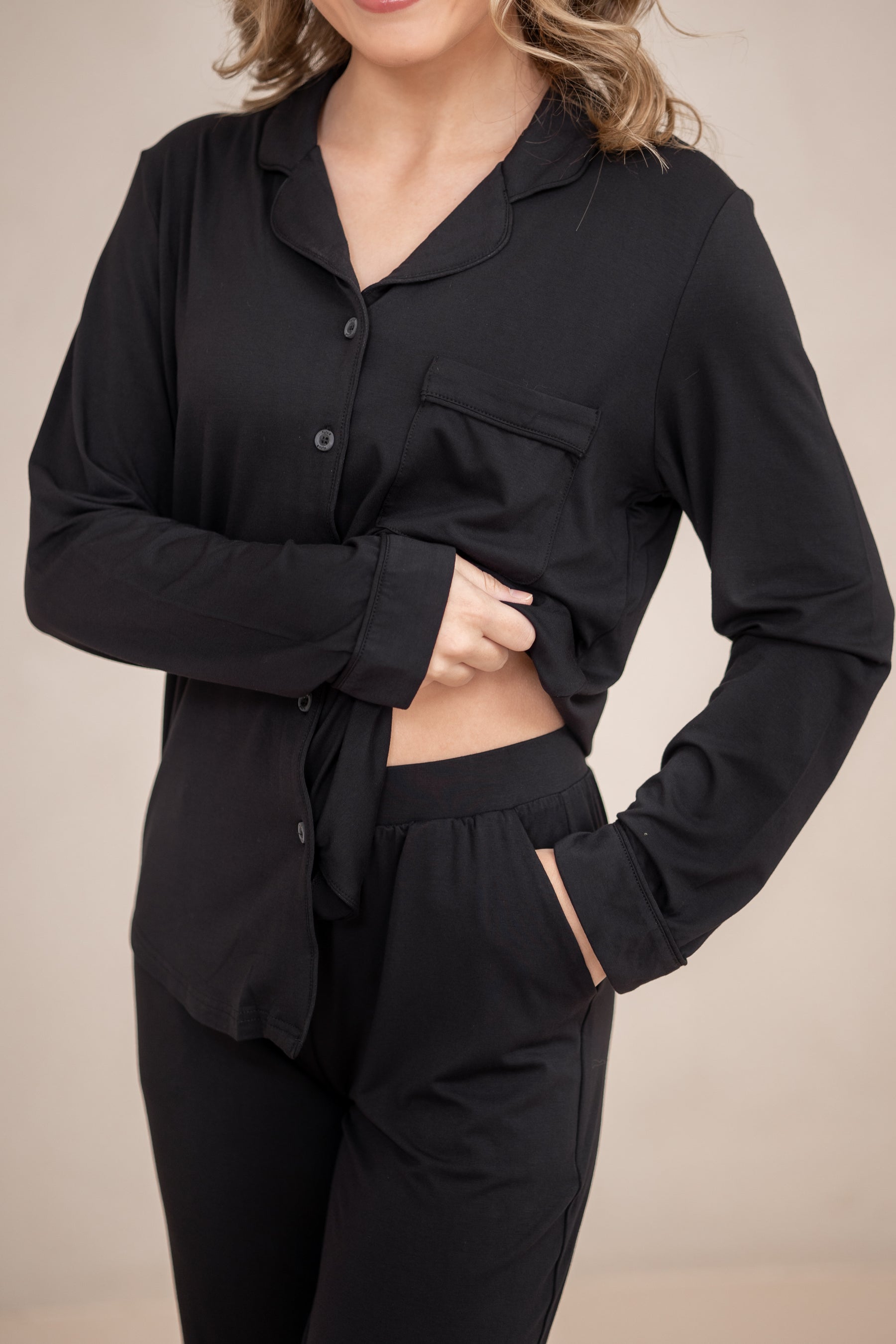 Female wearing the Long-Sleeved Women's Pajama Set in Midnight with Midnight Trim with one hand in the pants pocket and the shirt pulled up showing the elastic waistband