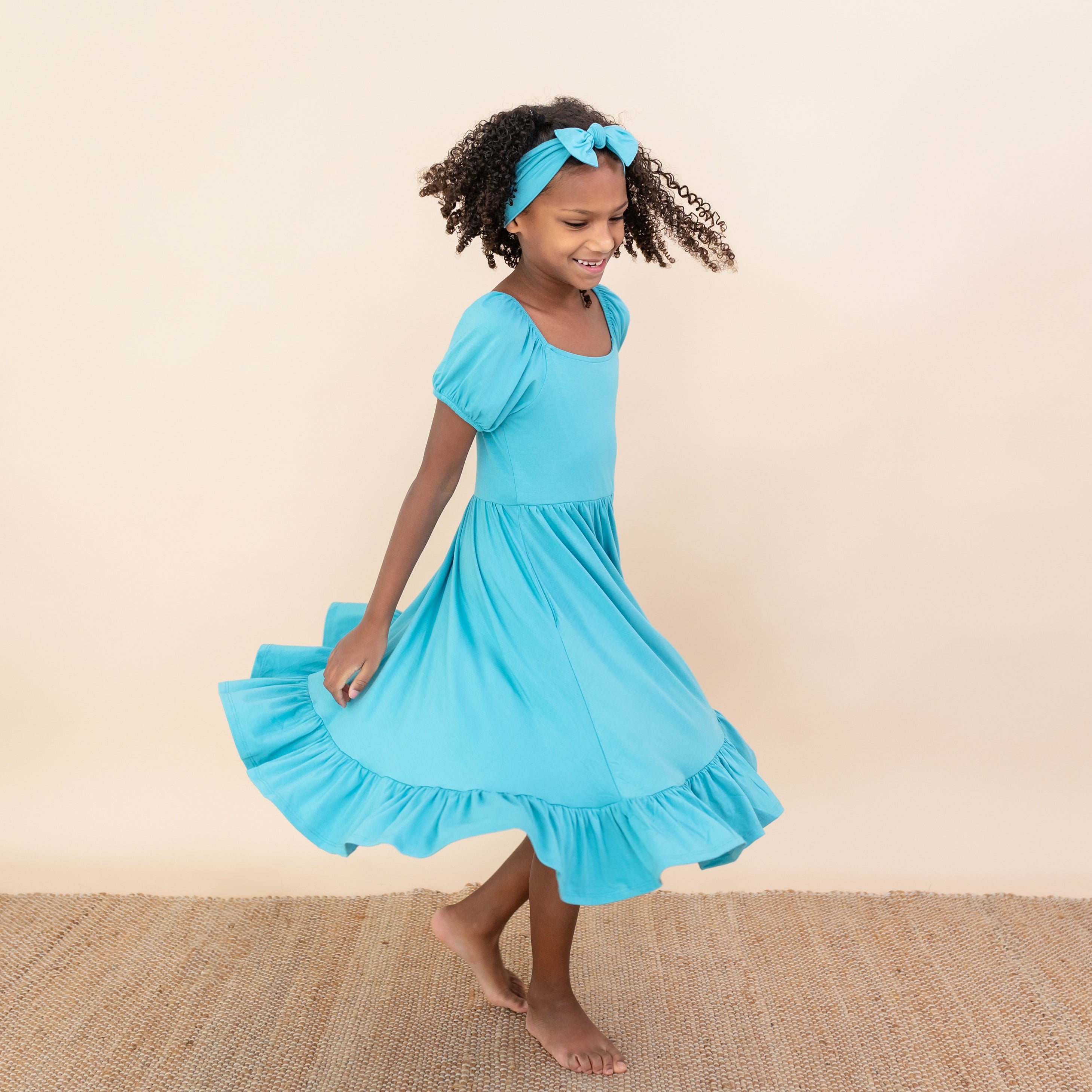 Child twirling in Puff Sleeve Twirl Dress in Makai