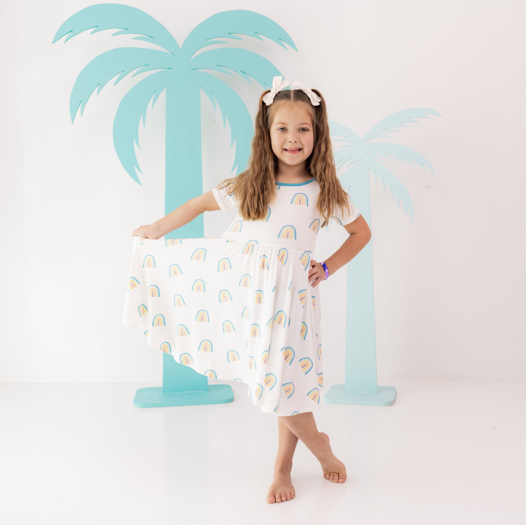 Toddler wearing Twirl Dress in Makai Rainbow in front of palm tree cut outs