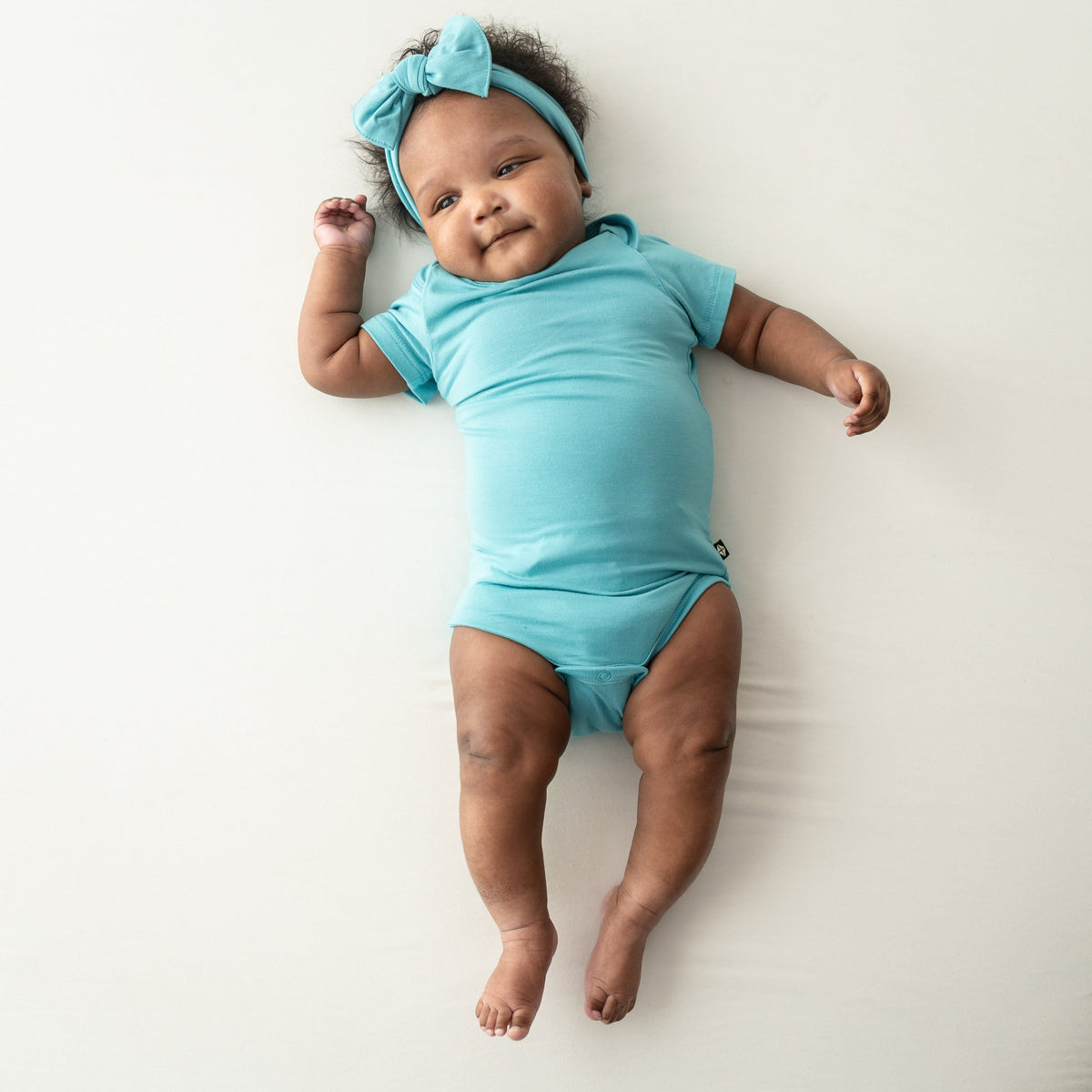 baby wearing short sleeve bodysuit and bow in makai 