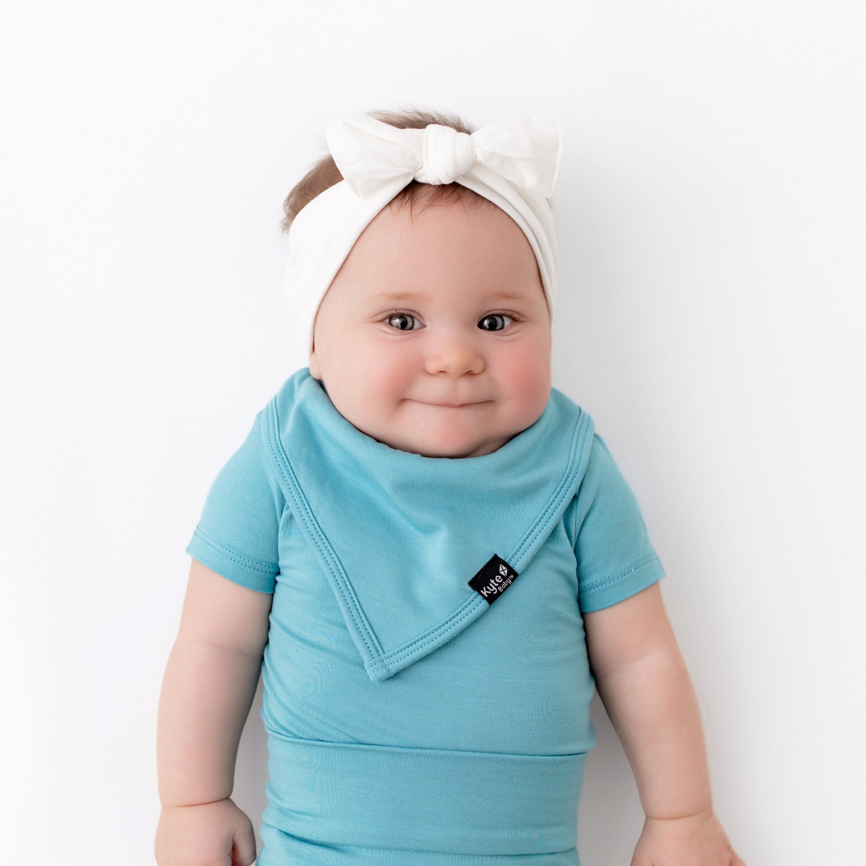 baby wearing kyte baby bodysuit in makai and matching bib