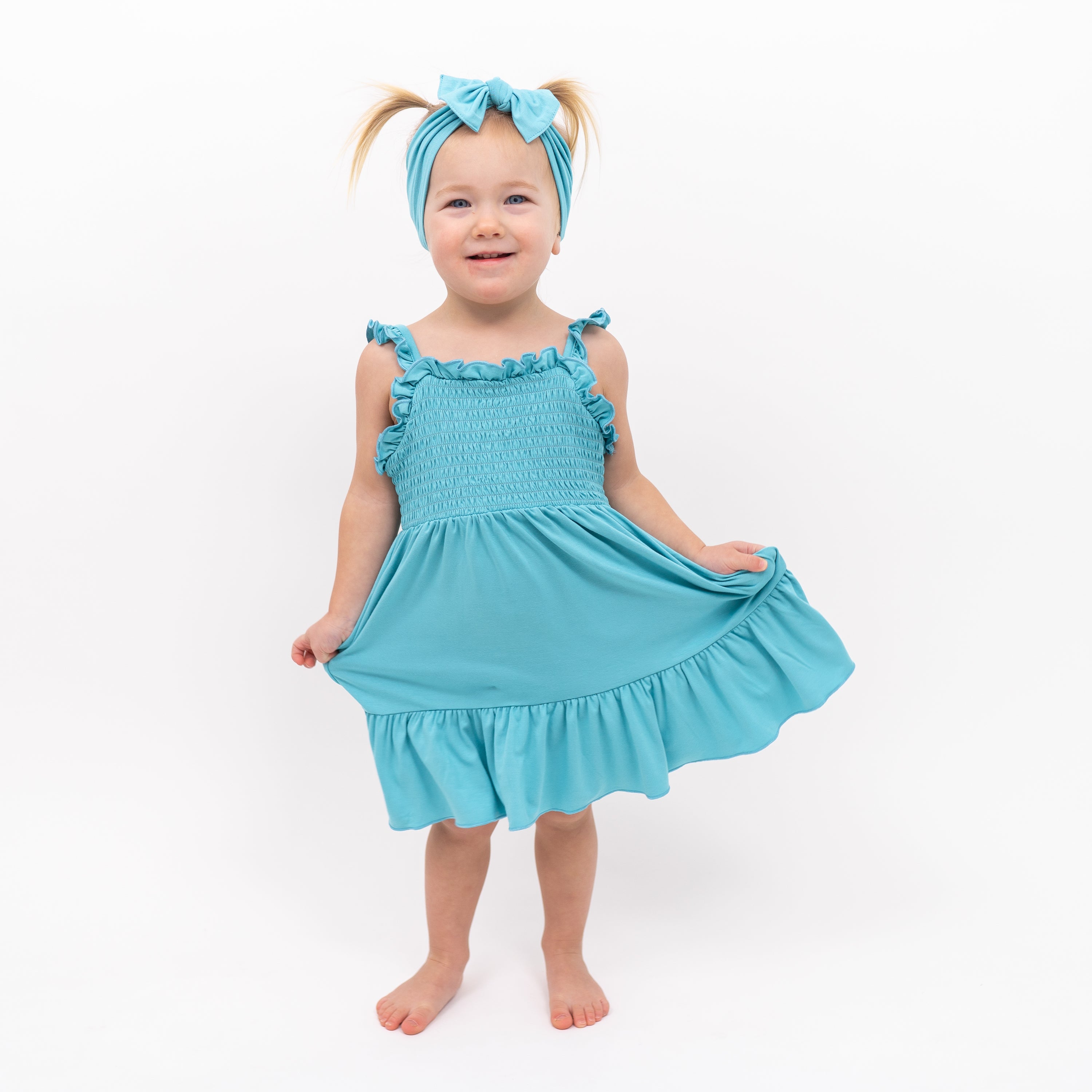 Toddler modeling Smocked Dress in Makai