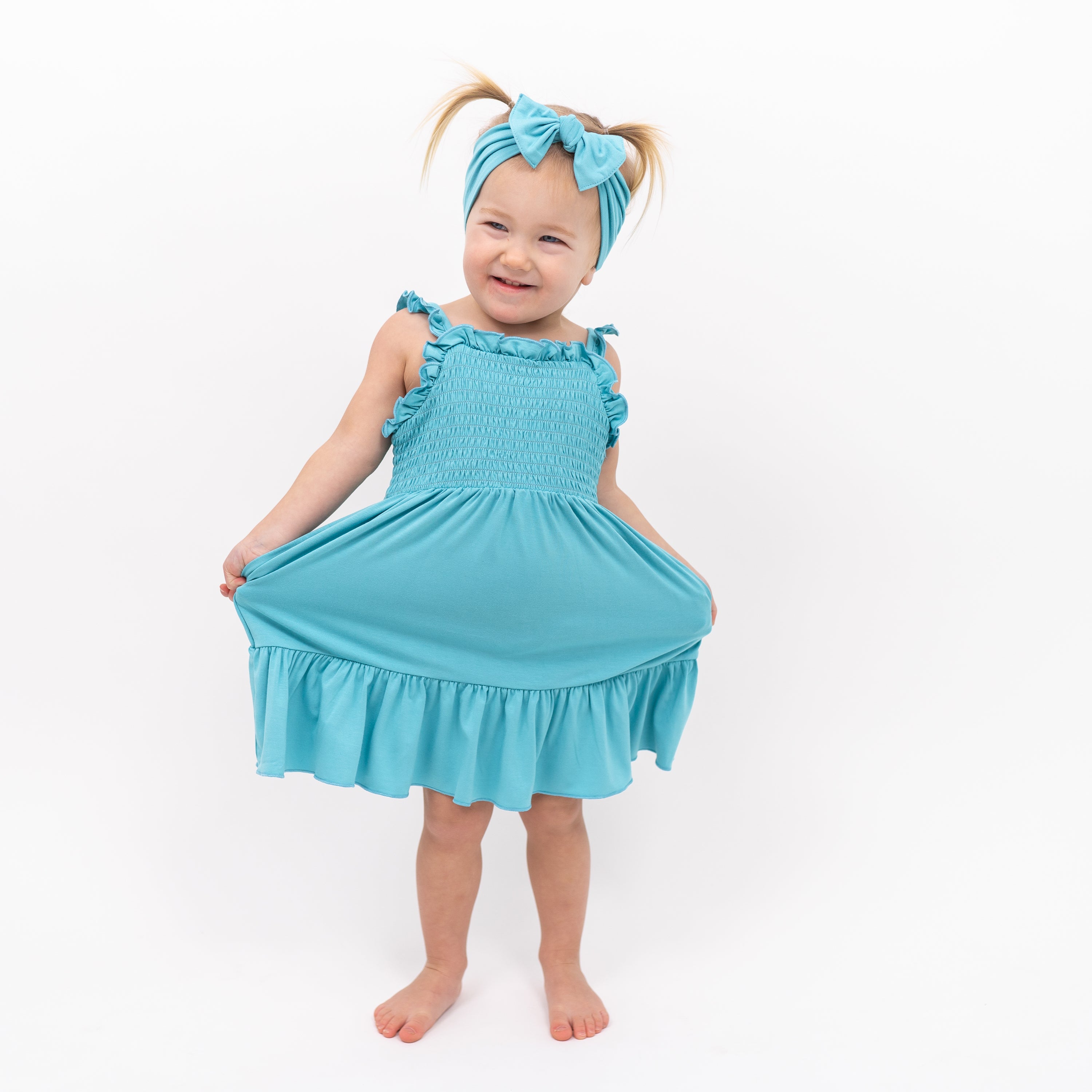 Toddler modeling Smocked Dress in Makai