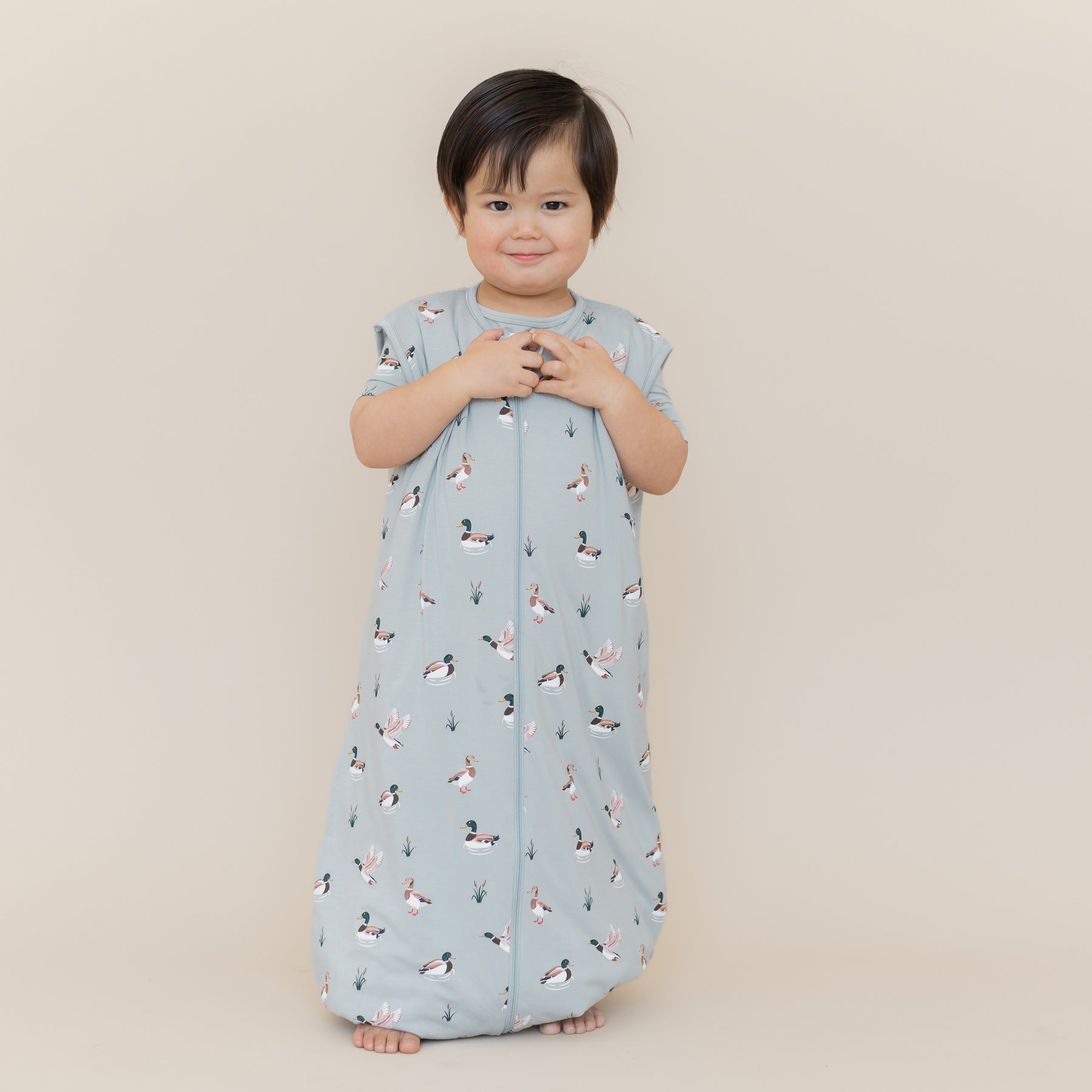 Young child standing wearing the Sleep Bag Walker in Mallard Duck 1.0 with matching short sleeve pajamas underneath