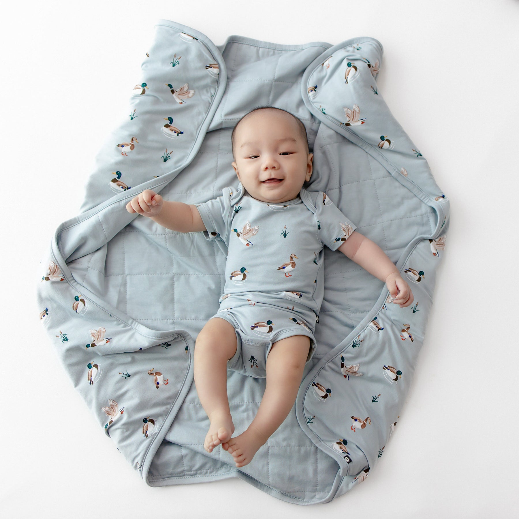 Infant laying on the Baby Blanket in Mallard Duck wearing a matching short sleeve bodysuit