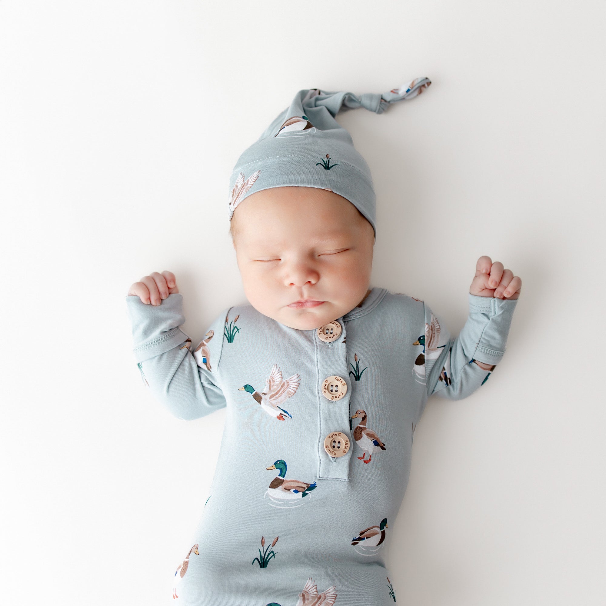 Close up of sleeping newborn wearing the Knotted Gown with Hat Set in Mallard Duck