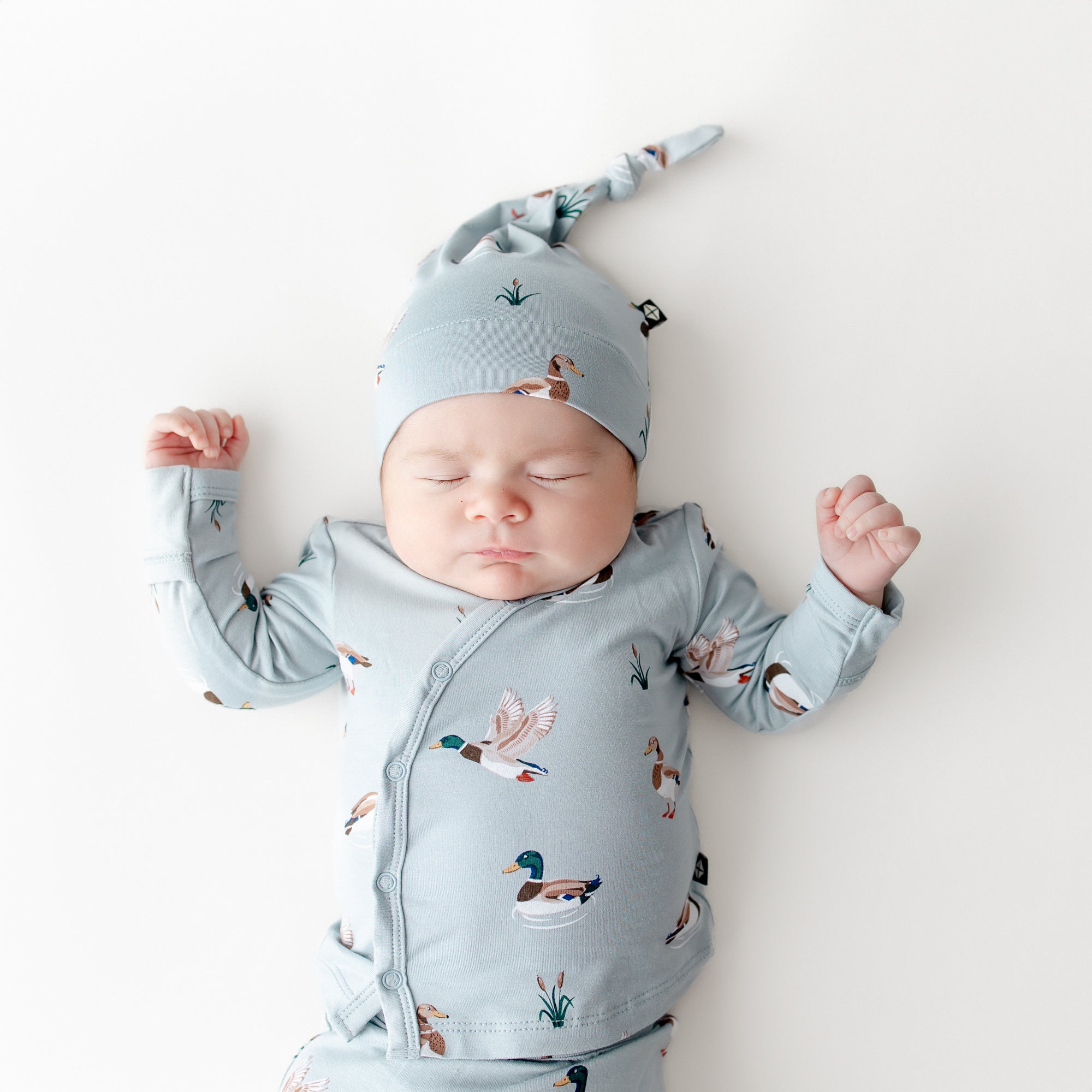 Close up of sleeping newborn wearing the Take Me Home Set with Cap in Mallard Duck