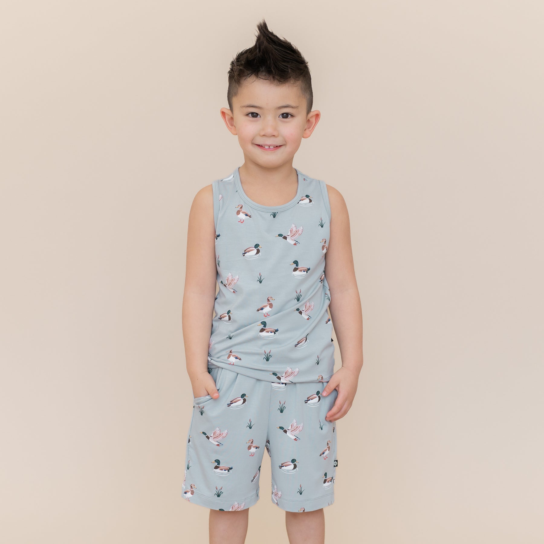 Smiling boy modeling the Toddler Tank Top in Mallard Duck and matching drawstring shorts in mallard duck