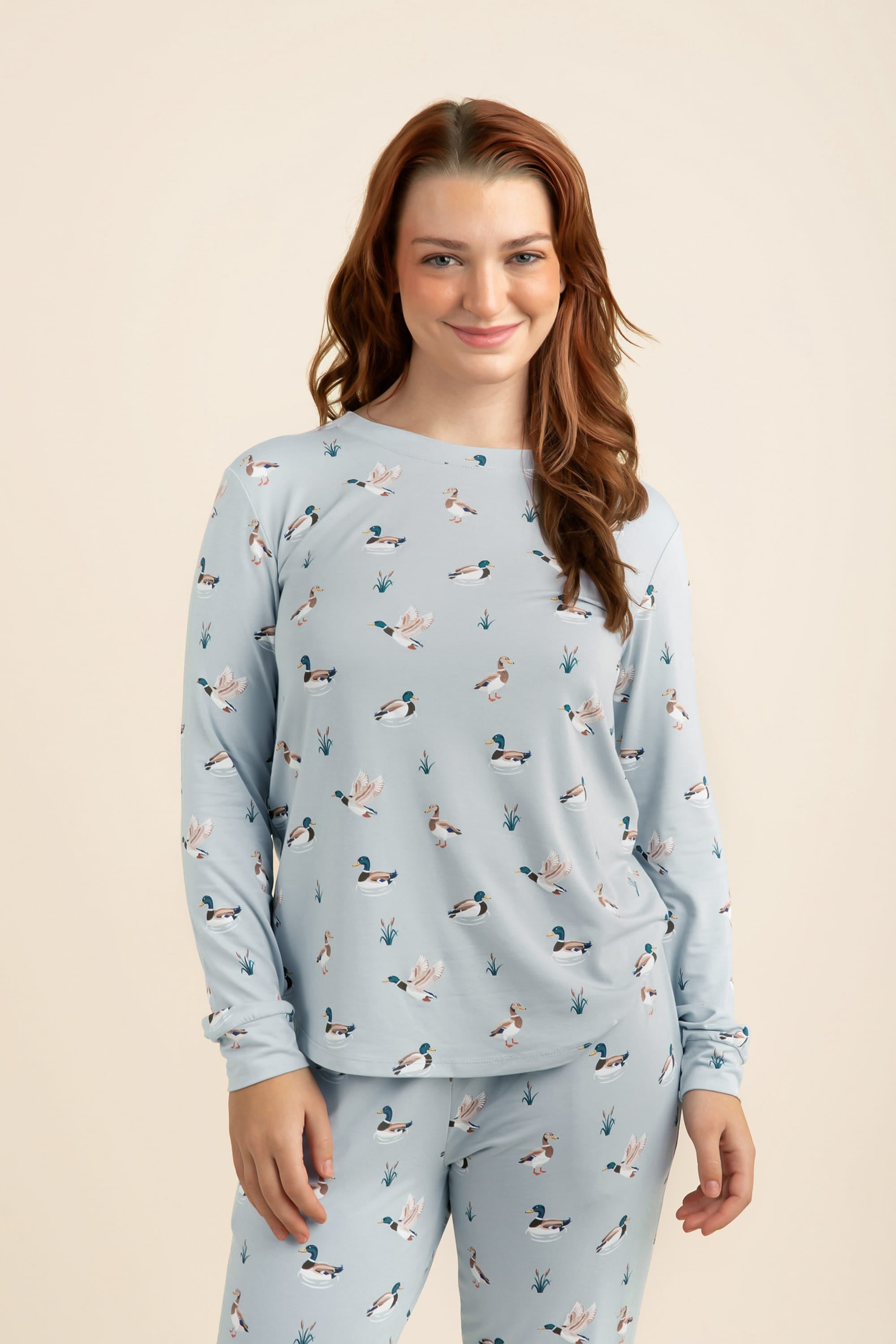 Woman wearing a light blue pajama set with a duck pattern on a beige background