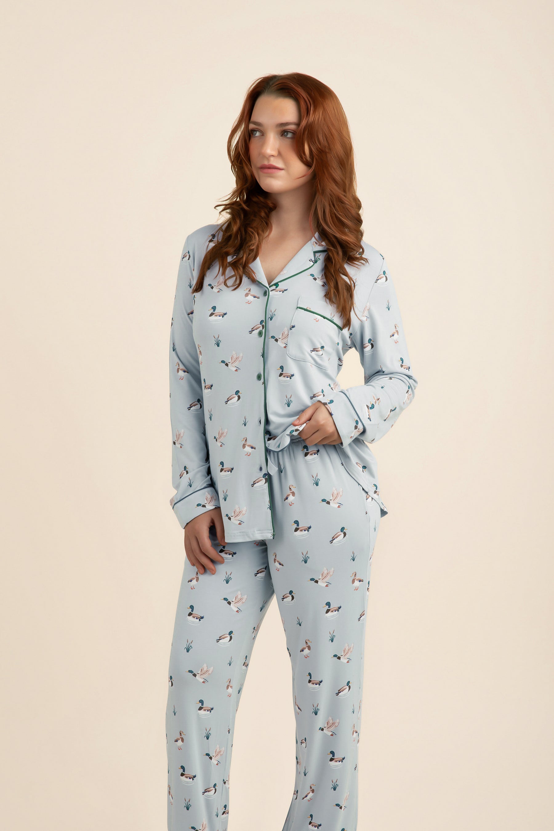 Woman wearing a light blue pajama set with duck pattern on a beige background