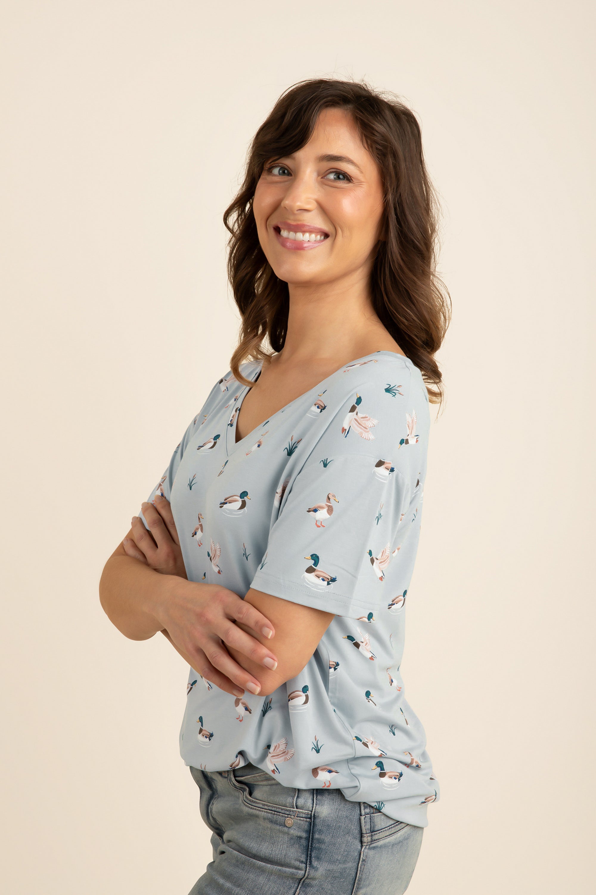 Woman wearing a light blue v-neck with a duck pattern on a beige background