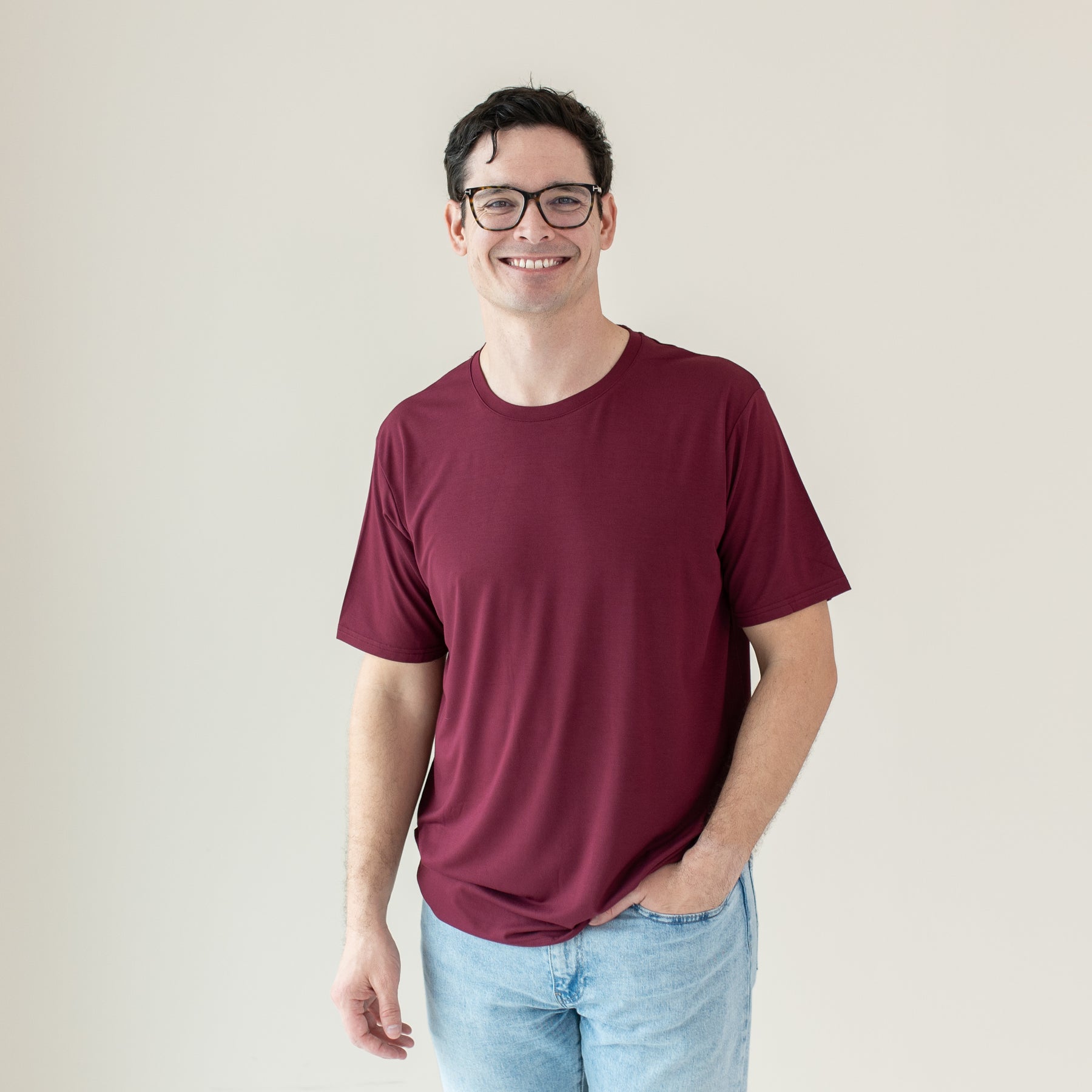 Smiling male wearing the Men's Crew Neck Tee in Burgundy with one hand in his jean pocket