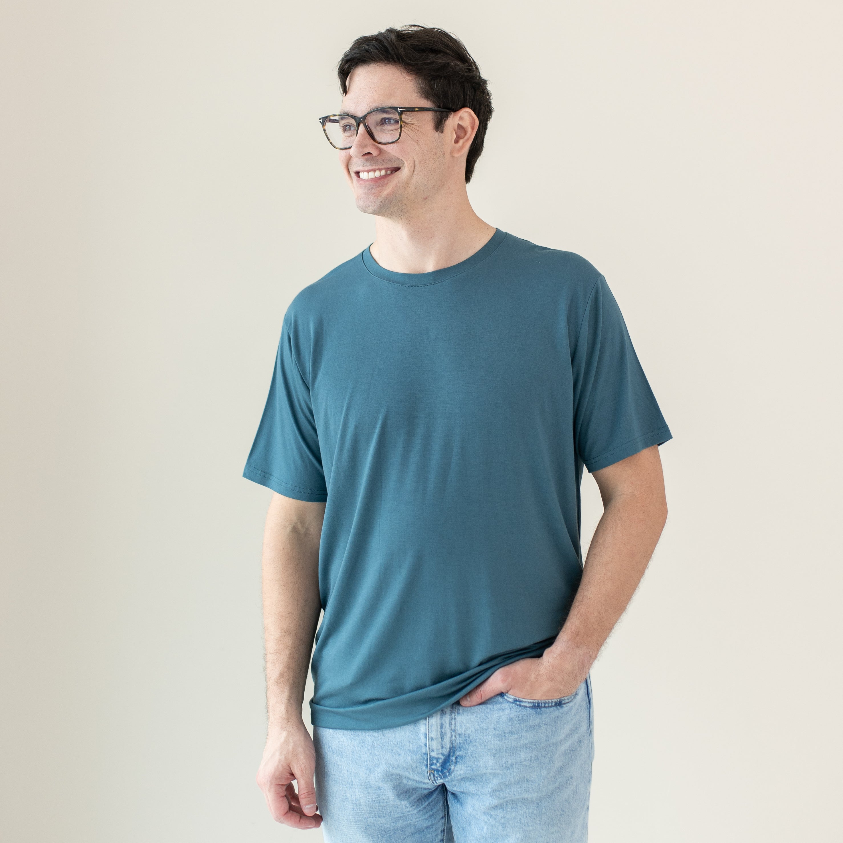 Smiling male model looking off to the side wearing the Men's Crew Neck Tee in Atlantic with one hand in his jeans pocket