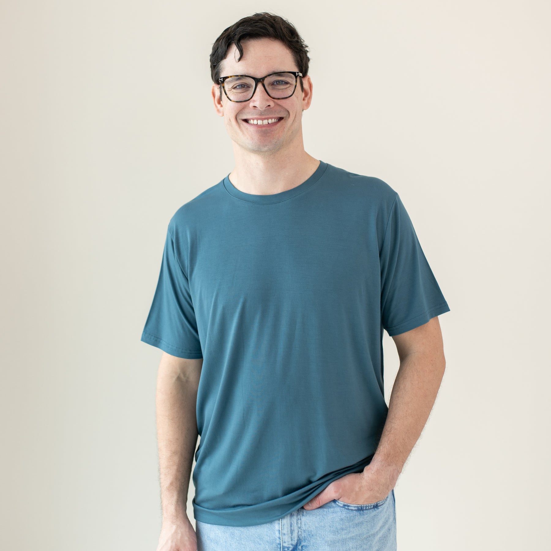 Smiling male model wearing the Men's Crew Neck Tee in Atlantic with one hand in his jean pocket