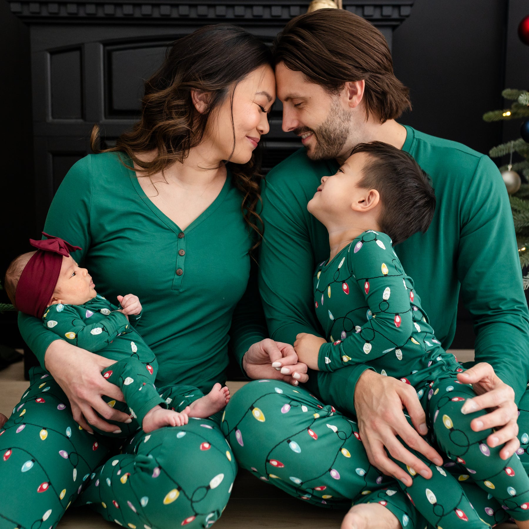 Family of four sitting on the floor matching in the Merry and Bright Holiday Print